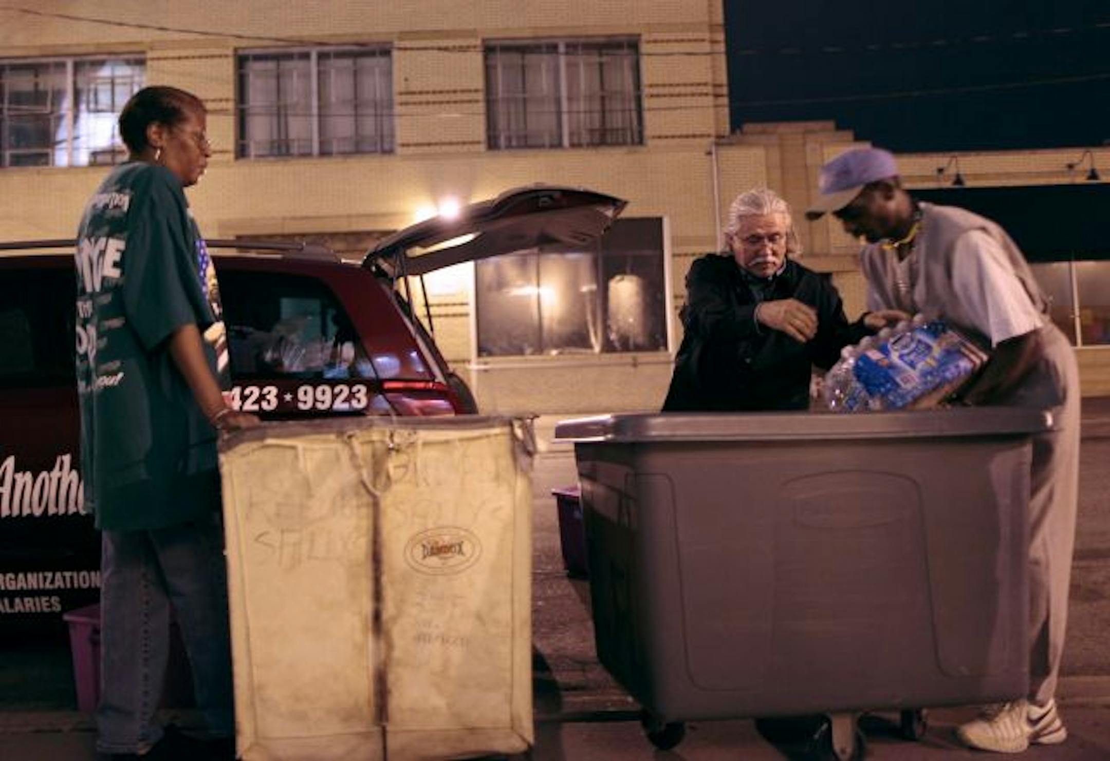 Allan Law fills bins with food for homeless people with the aid of Salvation Army employees Annette Sharp, left, and Steve Austin at right.