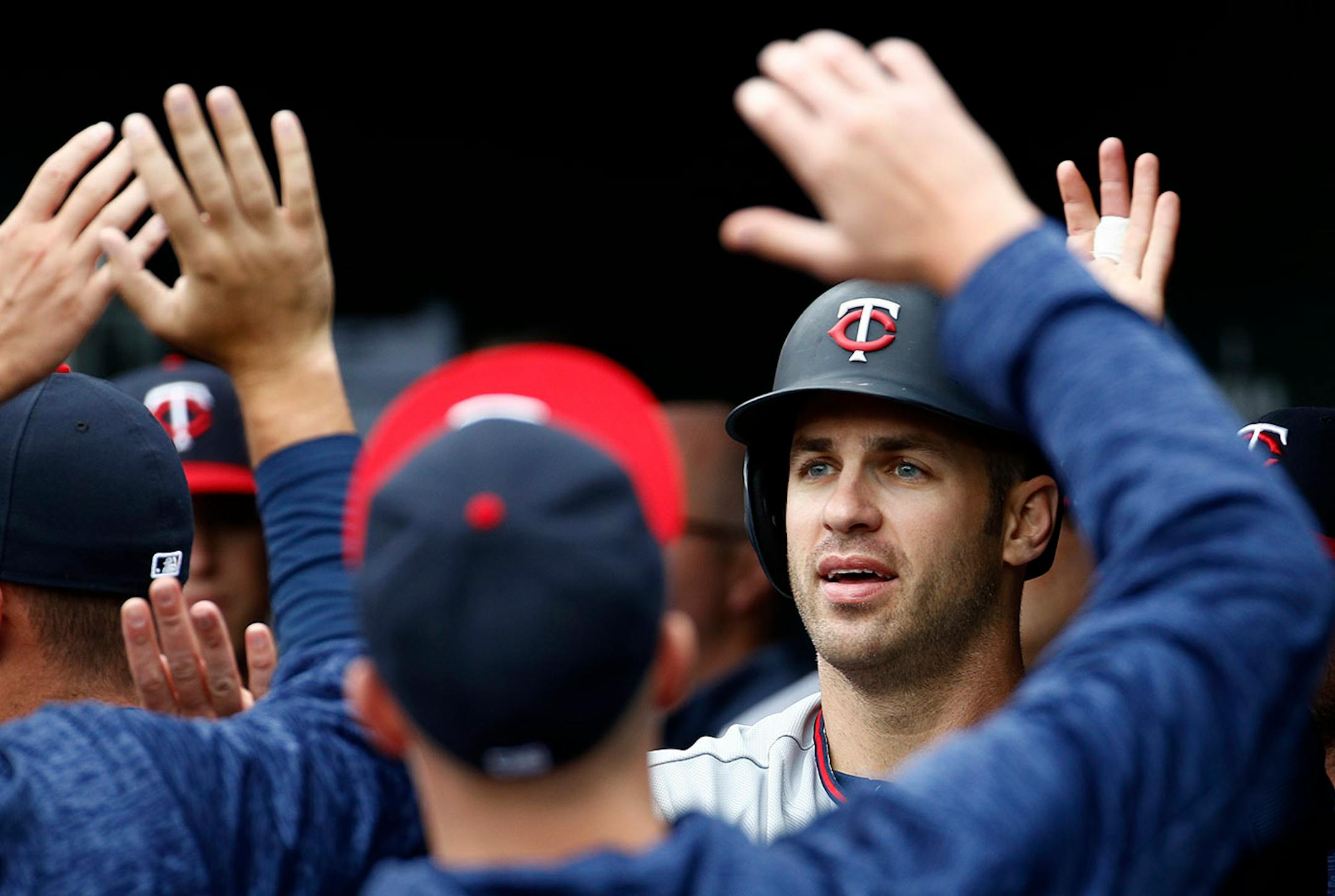 Minnesota Twins' Joe Mauer high-fives teammates in the dugout after scoring on a double by Eduardo Escobar in the first inning of a baseball game against the Baltimore Orioles, Sunday, April 1, 2018, in Baltimore.