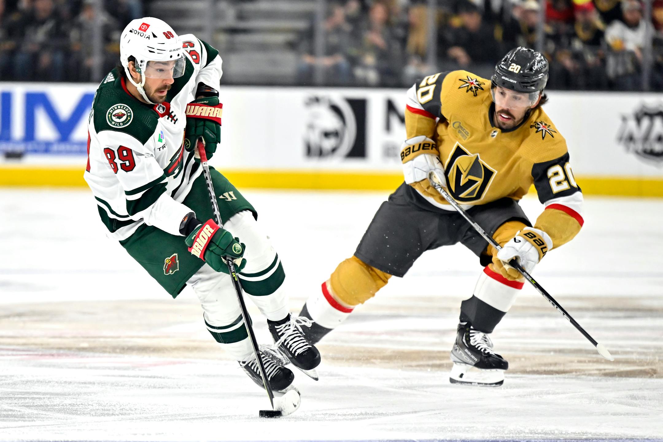 Minnesota Wild center Frederick Gaudreau (89) skates with the puck against Vegas Golden Knights center Chandler Stephenson during the first period of an NHL hockey game Saturday, April 1, 2023, in Las Vegas. (AP Photo/David Becker)