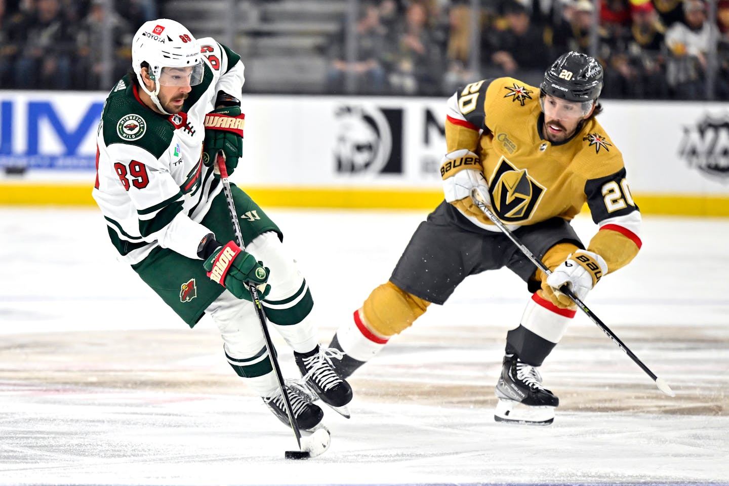 Minnesota Wild center Frederick Gaudreau (89) skates with the puck against Vegas Golden Knights center Chandler Stephenson during the first period of an NHL hockey game Saturday, April 1, 2023, in Las Vegas. (AP Photo/David Becker)