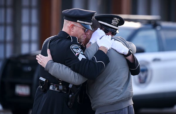 Taylor Jacobs, center, who was with Burnsville police for 10 years, embraced honor guard members Tuesday outside the Ballad-Sunder Funeral and Cremati