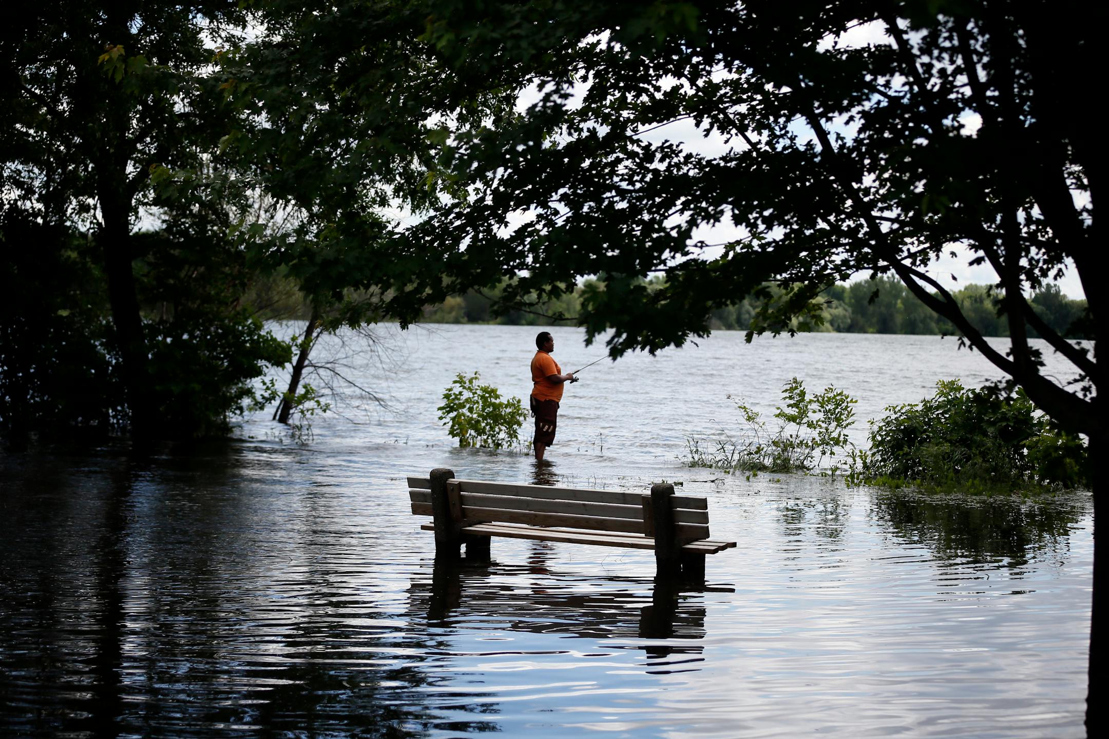 A fisherman on the flooded shoreline at Lake Nokomis earlier in June.