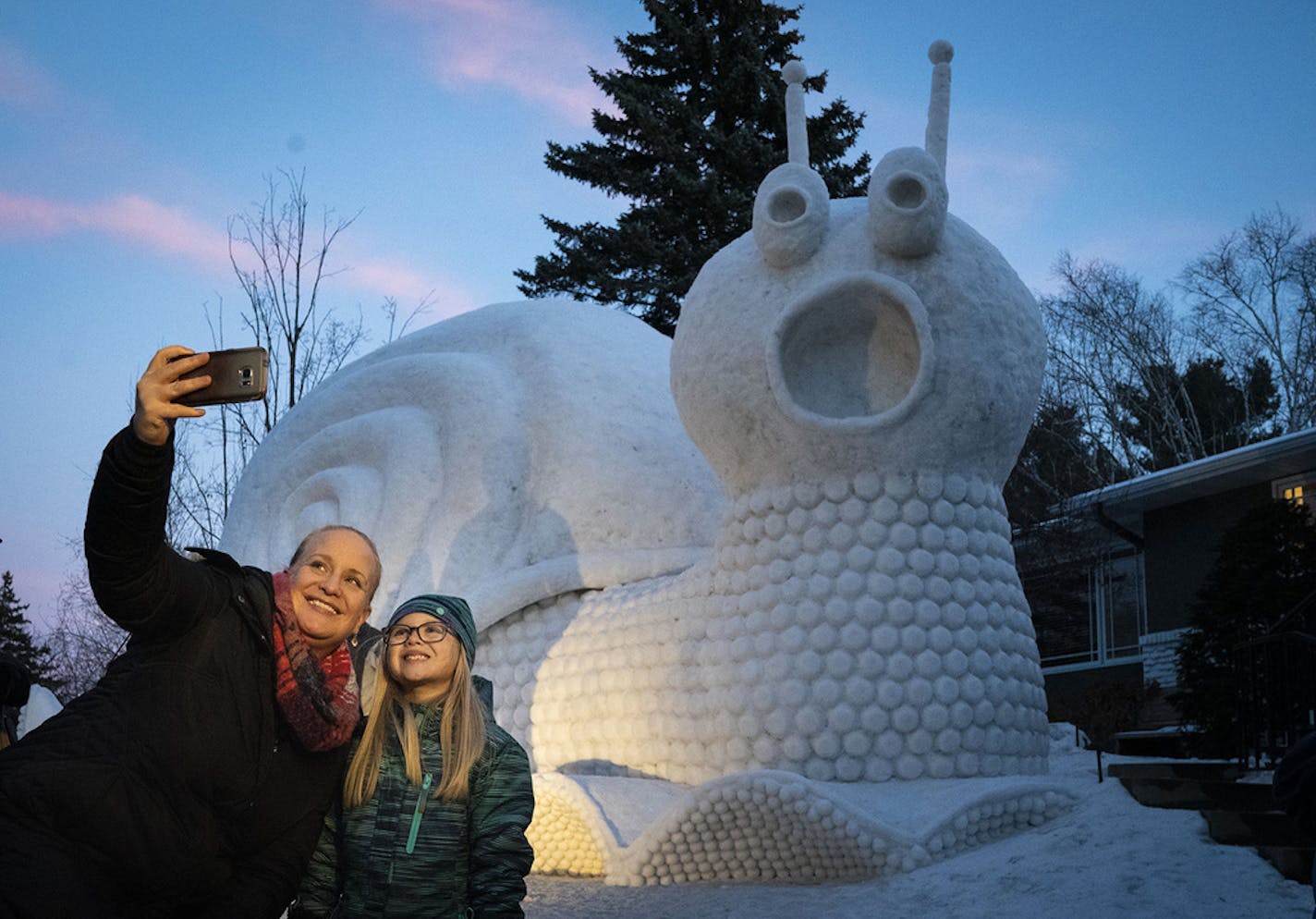 The Bartz Brothers unveiled their latest snow sculpture, a giant surprised snail, in front of their New Brighton, Minn., home this week. On Thursday, Jan. 3, 2019, multiple people drove or stopped by to take pictures and see the latest creation, including Kirsten Griebenow and her daughter MacKenna, 6, who took a selfie in front of the snow sculpture. (Renee Jones Schneider/Minneapolis Star Tribune/TNS)