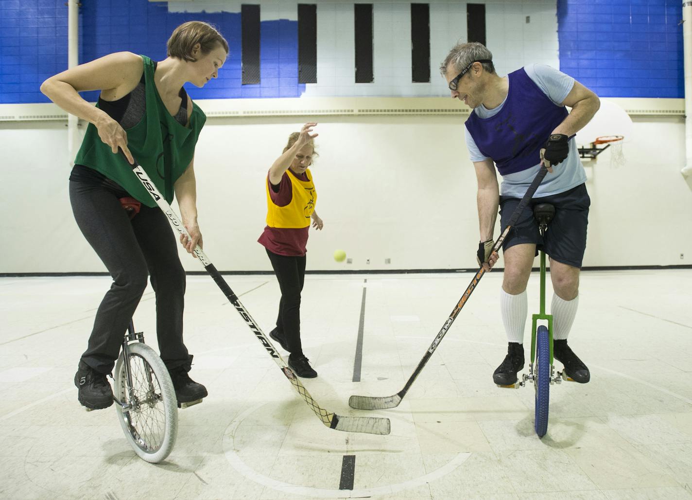 Julie Kovacic, center, dropped the ball as Irene Genelin and Garrett Macey faced off during the start of a unicycle hockey match on Jan. 24, at St. Matthew's Church in Columbia Heights. ] (AARON LAVINSKY/STAR TRIBUNE) aaron.lavinsky@startribune.com Minneapolis is home to some of the best unicyclists in the world. Who knew? Meet the zany members of the Twin Cities Unicyclists Club who practice year-round - playing unicycle hockey and basketball, juggling, unicycle racing and more. We photograph t