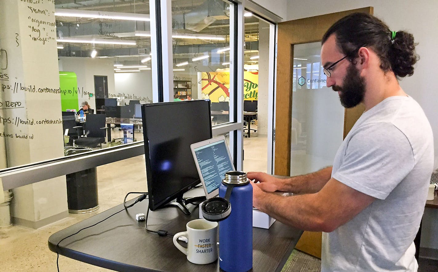 Nick Tate of ContainerShip, a cloud computing company on Pittsburgh's North Shore, stands about 50 percent of the day. In addition to stretching and working out, he stands at his desk about half of the day to mitigate back pain. (Matthew Gutierrez/Pittsburgh Post-Gazette/TNS)