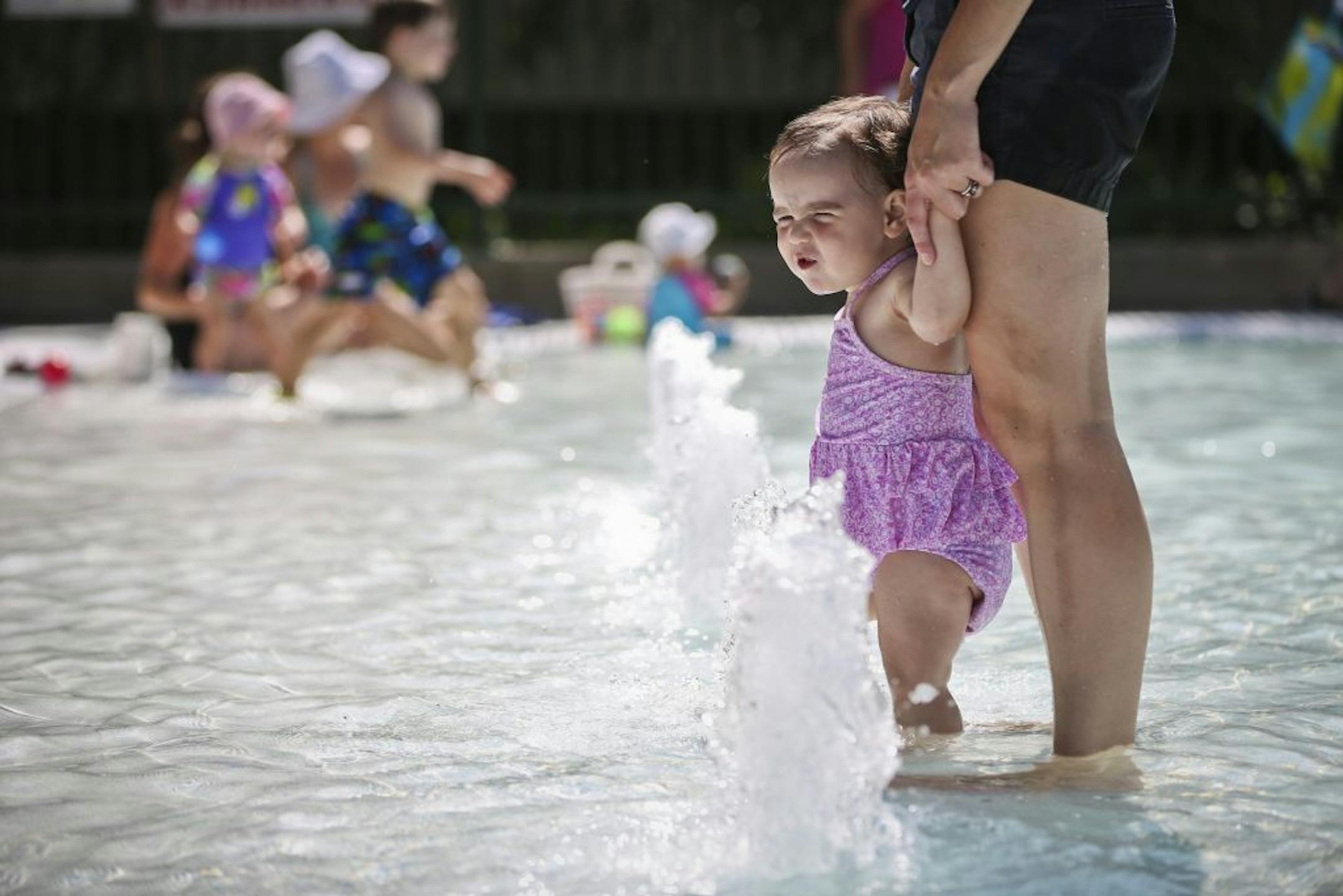 Emma Rose held the hands of her daughter Lucia Geyette, 15 months, as they played in a fountain at the Lake Hiawatha Park wading pool on Friday, July 20, 2012 in Minneapolis, Minn. The family was visiting family in Minnesota from Philadelphia.