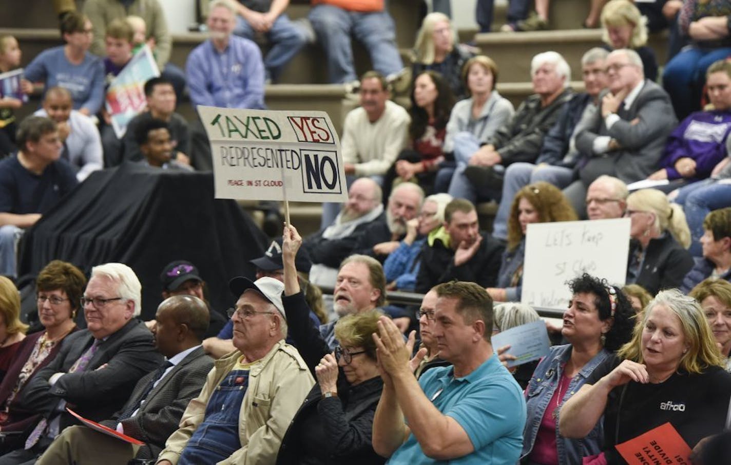 People hold signs during a St. Cloud City Council discussion on moratoriums related to refugee resettlement Monday, Oct. 23, 2017, at city council chambers in St. Cloud, Minn.