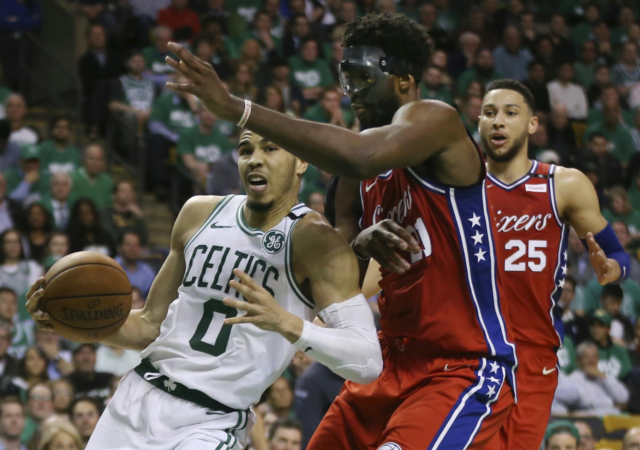 Boston Celtics forward Jayson Tatum (0) drives against Philadelphia 76ers center Joel Embiid (21) as 76ers guard Ben Simmons (25) looks on in the second half of Game 1 of an NBA basketball second-round playoff series, Monday, April 30, 2018, in Boston. The Celtics won 117-101. (AP Photo/Elise Amendola)
