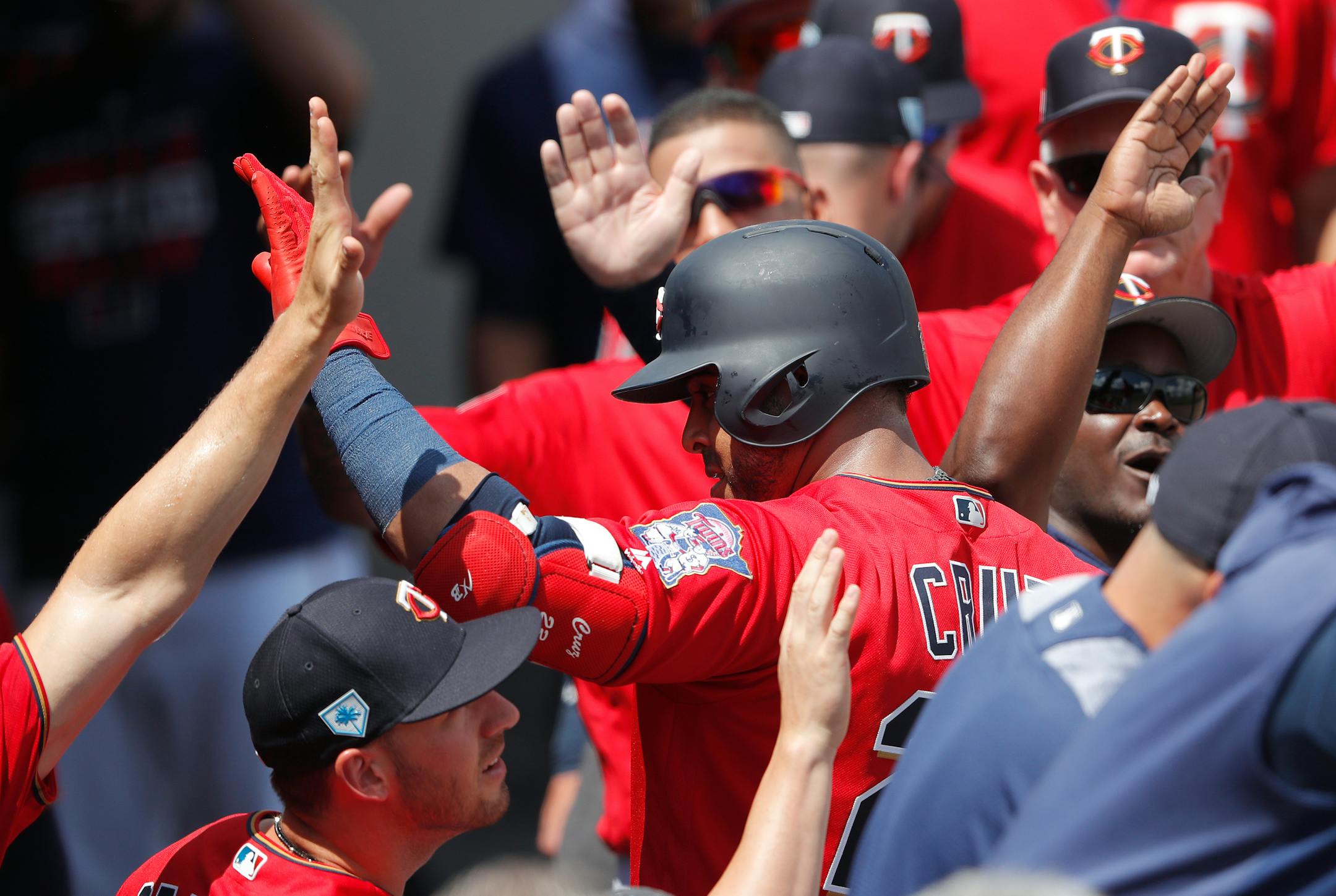 Minnesota Twins designated hitter Nelson Cruz, center, celebrates as he returns to the dugout after hitting a two-run home run in the first inning of a spring training baseball game against the Colorado Rockies Tuesday, March 26, 2019, in Fort Myers, Fla. (AP Photo/John Bazemore)