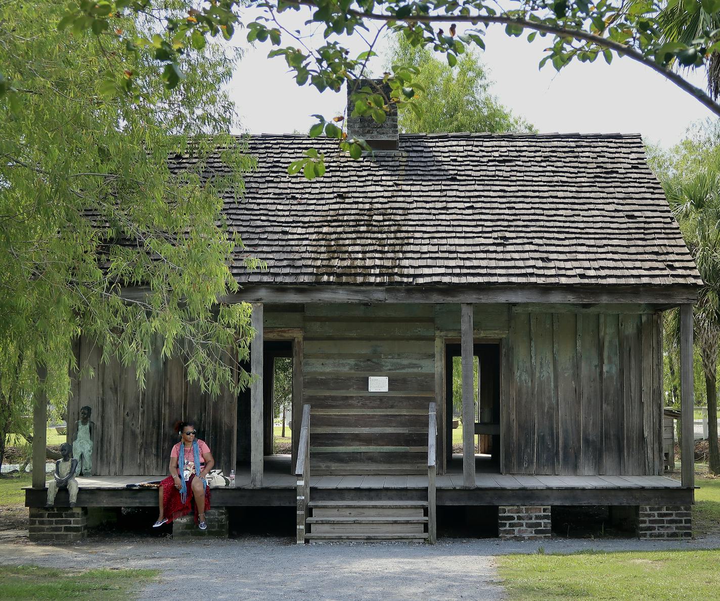 A bitter harvest: A visitor rests on the porch of a cabin, at top, where slaves crammed in when they weren't toiling in the fields or mills to produce sugar. Above, a jail for runaways looks onto the Big House, aka the mansion.