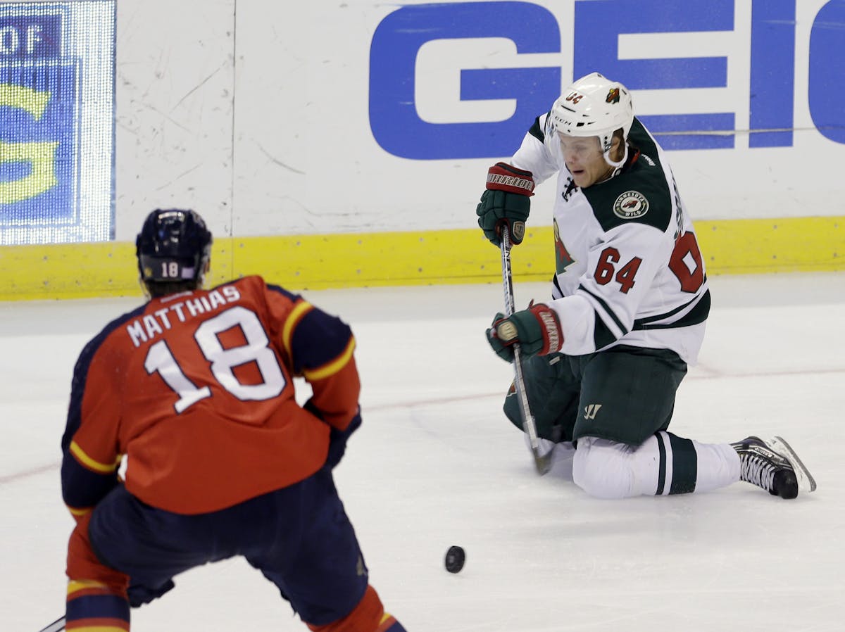 Minnesota Wild's Mikael Granlund (64) goes down as he drives against Florida Panthers' Shawn Matthias (18) in the first period of an NHL hockey game o