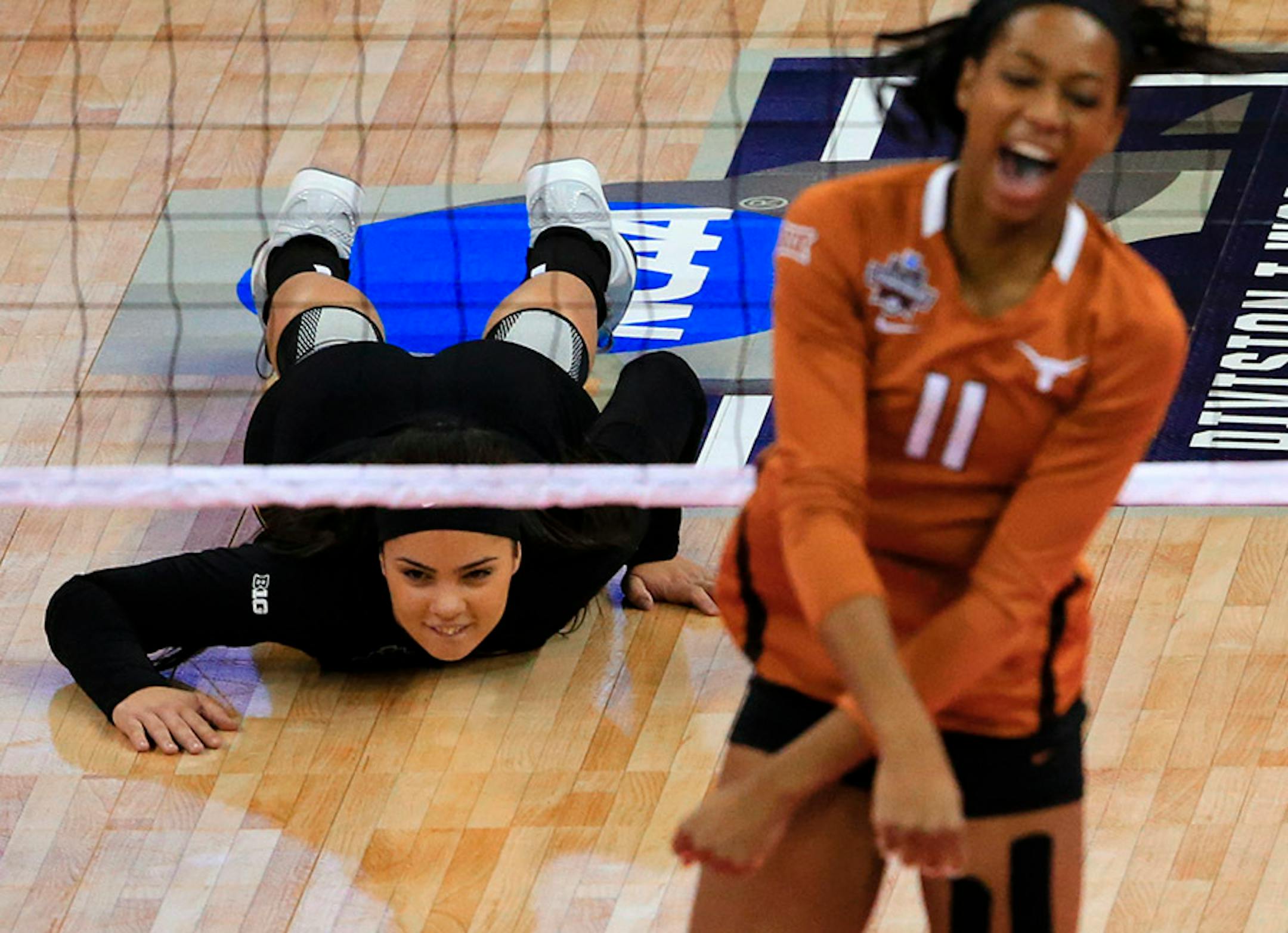 Minnesota's Dalianliz Rosado lies on the court as Texas' Chiaka Ogbogu (11) celebrates a kill during an NCAA women's volleyball tournament semifinal in Omaha, Neb., Thursday, Dec. 17, 2015.