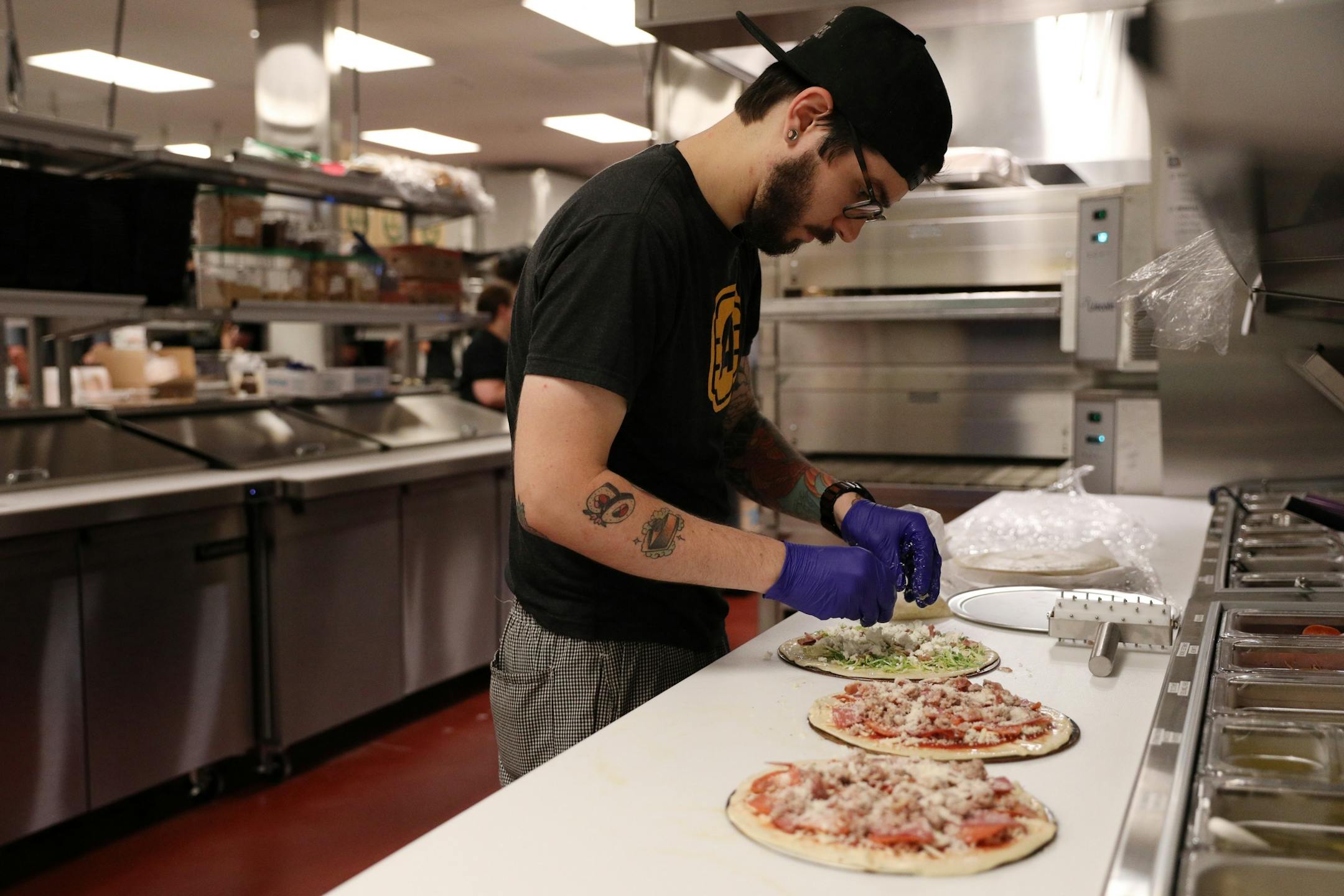 Kitchen manager Cameron McGuire fixed a trio of pizzas in the kitchen at Alamo Drafthouse Cinema.