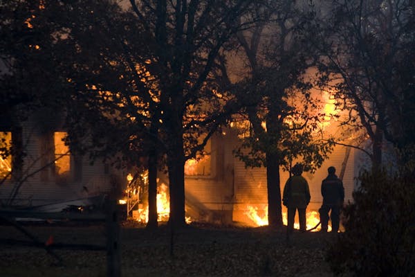 A fire consumes a house in Karlstad, Minn., Tuesday evening after wildfires fueled by high winds and dry conditions spread quickly.