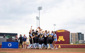 St. Cloud Cathedral players swarm their trophy after defeating Hawley 7-2 Friday in the Class 2A championship game at Jane Sage Cowles Stadium.