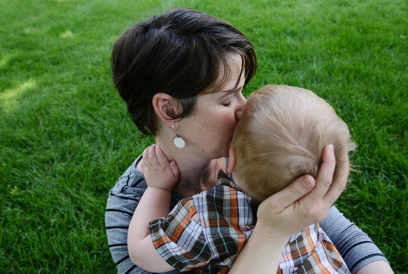 Wyatt Hauser, 3, is kissed by his mother, Jessica Hauser, in their backyard in Woodbury, Minn., on Sunday June 14, 2015. Wyatt has infantile spasms, a form of epilepsy that causes 100 to 200 seizures per day. He wears a helmet when he is more than a few steps away from his parents to prevent falling forward during seizures.