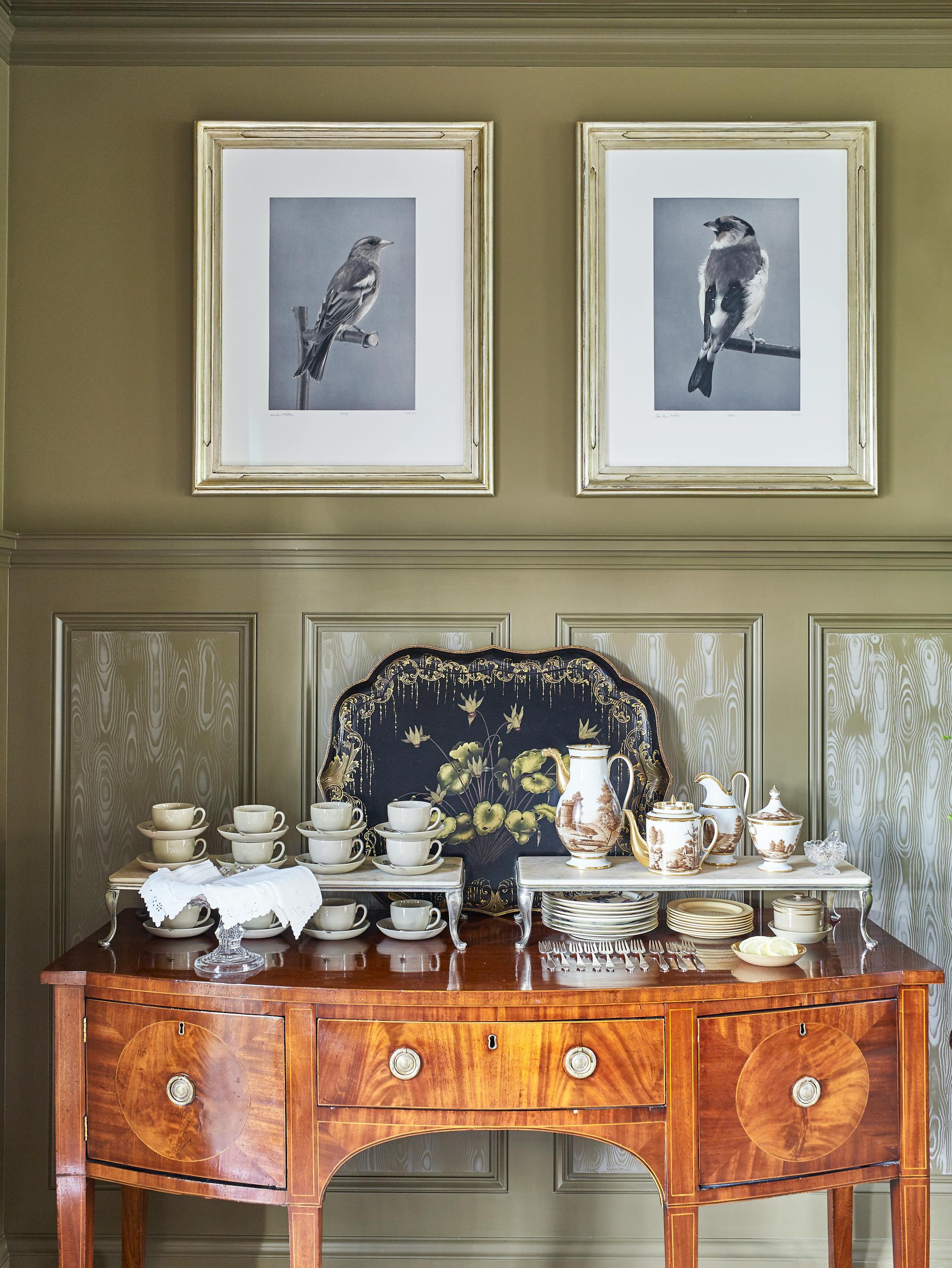 BC-ASK-MARTHA-BEDFORD-INTERIORS-ART-NYTSF — In the main dining room (aka the Brown Room), an antique sideboard from Skylands, Martha's Maine home, holds early-American silver and a Paris porcelain coffee service to keep her team caffeinated. "Silver really brightens up a tabletop; it doesn't have to be fuddy-duddy," she says. "If your grandma gives you a beautiful set, use it." To double the display space, old chafing-dish bases were topped with two leftover marble stair treads that were cut to fit. The English tray behind it is from an antiques sale; the framed photographs are by Carsten Höller. (Pieter Estersohn/Martha Stewart Living Online) — ONLY FOR USE WITH ARTICLE SLUGGED — BC-ASK-MARTHA-BEDFORD-INTERIORS-ART-NYTSF — OTHER USE PROHIBITED.