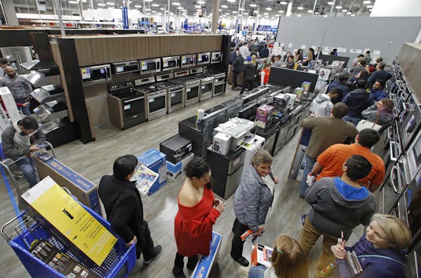 FILE- In this Nov. 22, 2018, file photo people line up to pay for their purchases as they shop during an early Black Friday sale at a Best Buy store o
