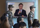 South Korean marines walk by a TV screen showing the live broadcast of South Korean President Moon Jae-in's press conference, at the Seoul Railway Sta