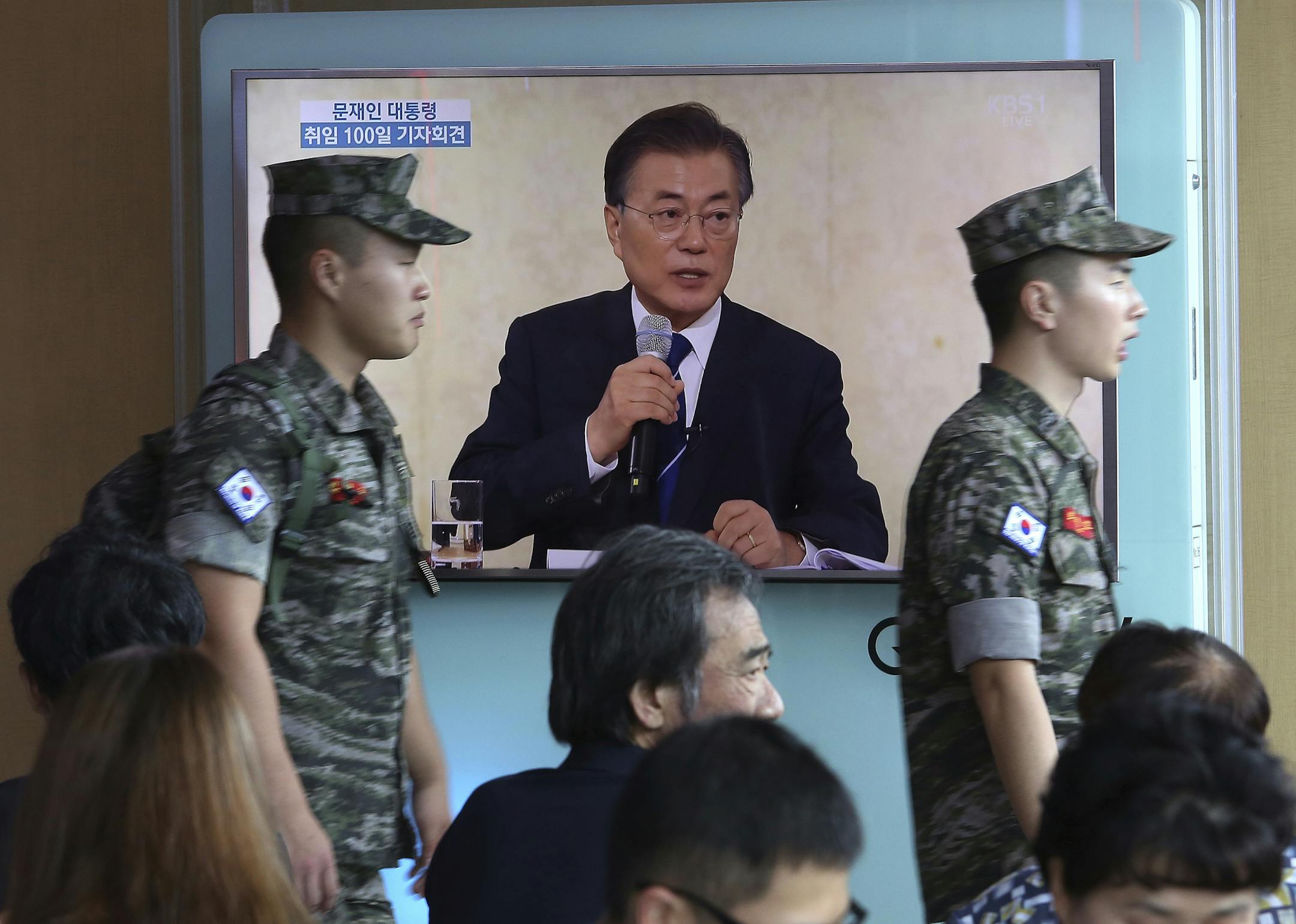 South Korean marines walk by a TV screen showing the live broadcast of South Korean President Moon Jae-in's press conference, at the Seoul Railway Station in Seoul, South Korea, Thursday, Aug. 17, 2017. In an effort to jumpstart diplomacy, South Korean President Moon said Thursday he would consider sending a special envoy to North Korea for talks if the North stops its missile and nuclear tests. (AP Photo/Ahn Young-joon)