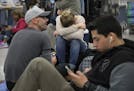 Delta passengers sits on the floor while waiting in line at Hartsfield-Jackson International Airport after Delta Air Lines grounded all domestic fligh