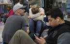 Delta passengers sits on the floor while waiting in line at Hartsfield-Jackson International Airport after Delta Air Lines grounded all domestic fligh