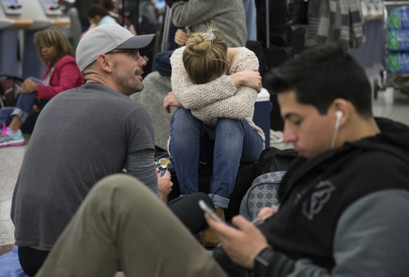 Delta passengers sits on the floor while waiting in line at Hartsfield-Jackson International Airport after Delta Air Lines grounded all domestic flights due to automation issues, Sunday, Jan. 29, 2017, in Atlanta.