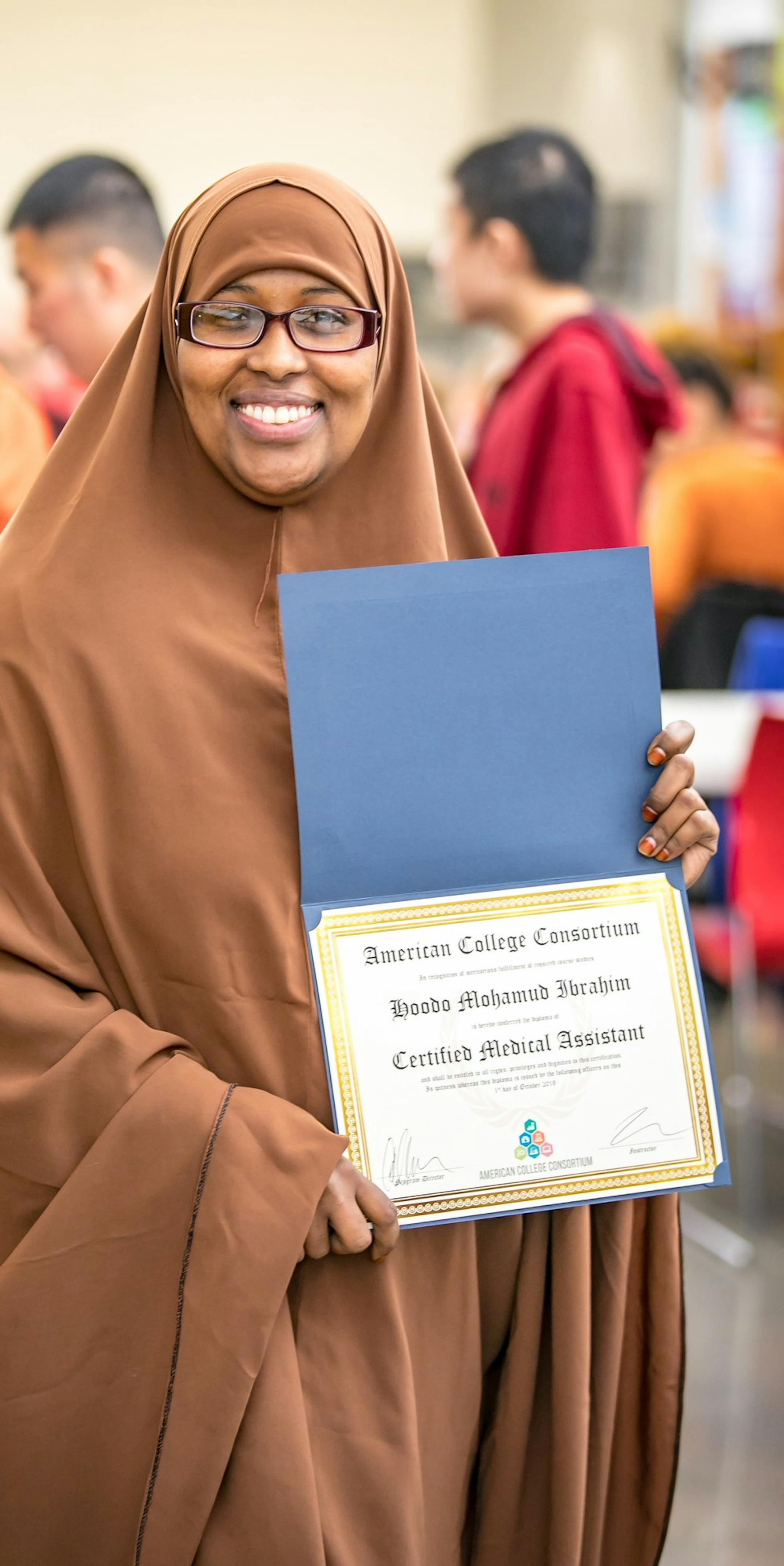 Hoodo Ibrahim holds up her diploma at a graduation celebration at Amazon.com's fulfilment center in Shakopee, Minn., on Oct. 1, 2019, In all, 88 Amazon employees became the first class to complete the company's Career Choice program in which it pays 95 percent of tuition costs for its workers to earn associate's degrees or professional certification for jobs inside or outside of the company.