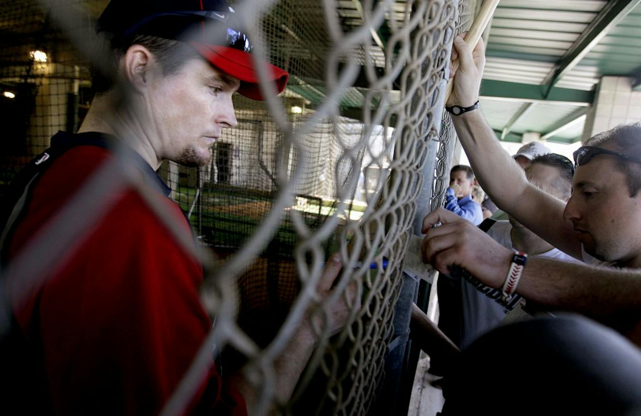 Minnesota Twins' Josh Willingham, left, signs autographs through the fence of the batting cage during a baseball spring training workout Friday, Feb. 24, 2012, in Fort Myers, Fla.