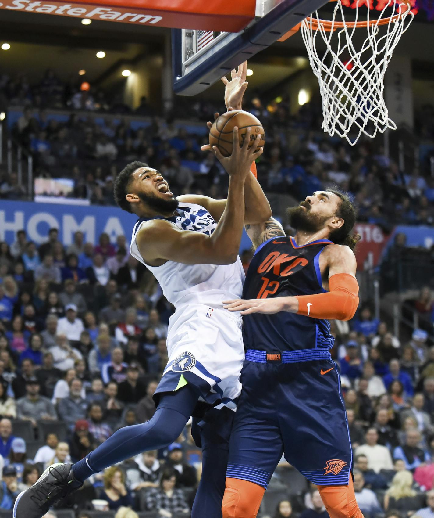 Minnesota Timberwolves center Karl-Anthony Towns, left, goes up to shoot over Oklahoma City Thunder center Steven Adams, right, in the first half of an NBA basketball game in Oklahoma City, Sunday, Dec. 23, 2018. (AP Photo/Kyle Phillips)