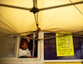 Durall Chappell, 6, helps hold down the tent in front of the Shakey Bonez food truck as the wind picks up Saturday at St. Paul's Rondo Days festival.