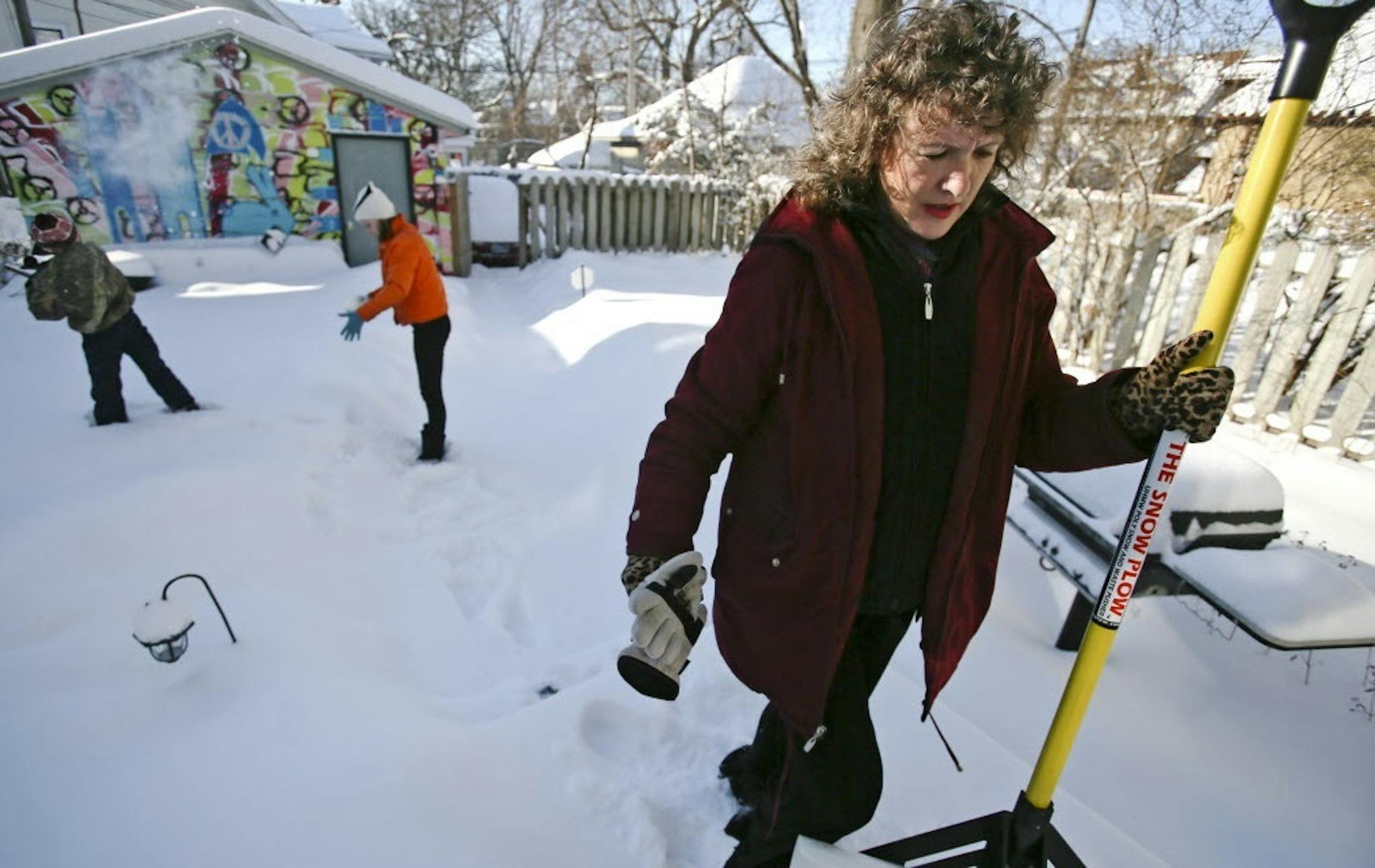 Mikki Morrissette prepares to shovel her walks after a winter snowstorm as her children Sophia, middle, and Dylan, left, test the snow Saturday, Jan. 18, 2014, outside Morrissette's Minneapolis home.