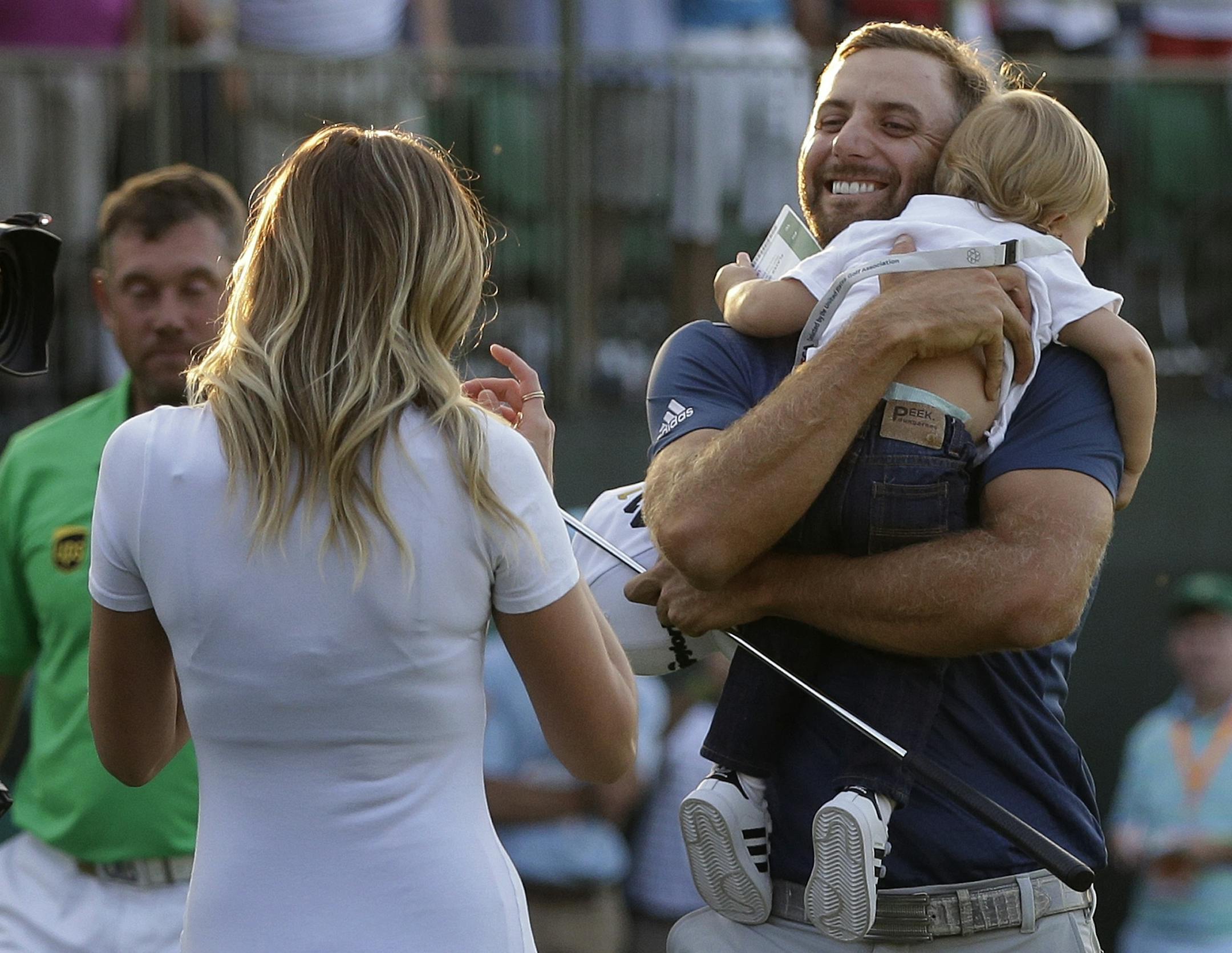 Dustin Johnson, right, greets his fiancÈí Paulina Gretzky as he holds their son Tatum Gretzky on the 18th hole during the final round of the U.S. Open golf championship at Oakmont Country Club on Sunday, June 19, 2016, in Oakmont, Pa. (AP Photo/John Minchillo)