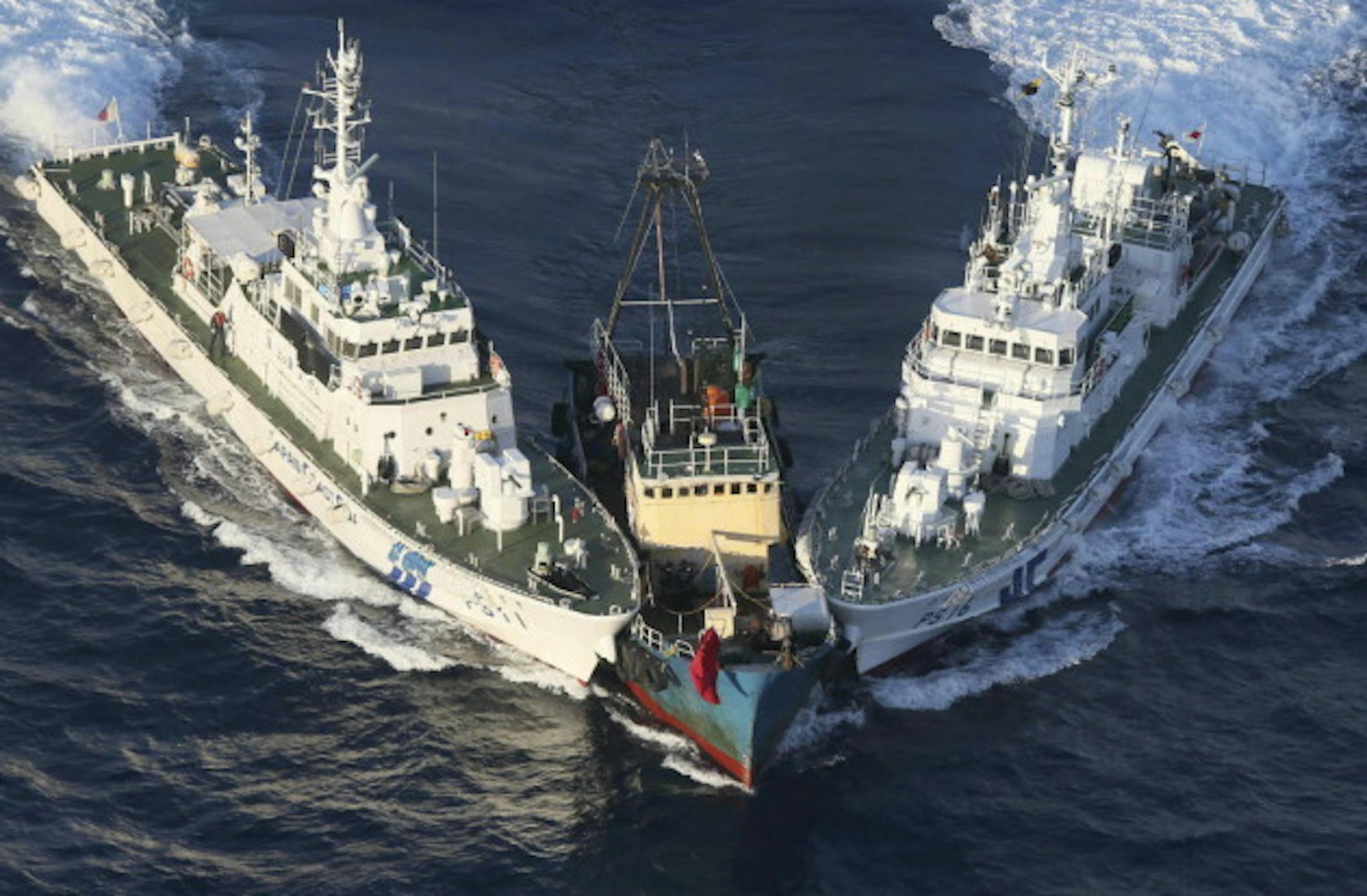 A boat, center, is surrounded by Japan Coast Guard's patrol boats after some activists descended from the boat on Uotsuri Island, one of the islands of Senkaku in Japanese and Diaoyu in Chinese, Wednesday, Aug. 15, 2012. (AP Photo/Yomiuri Shimbun, Masataka Morita)