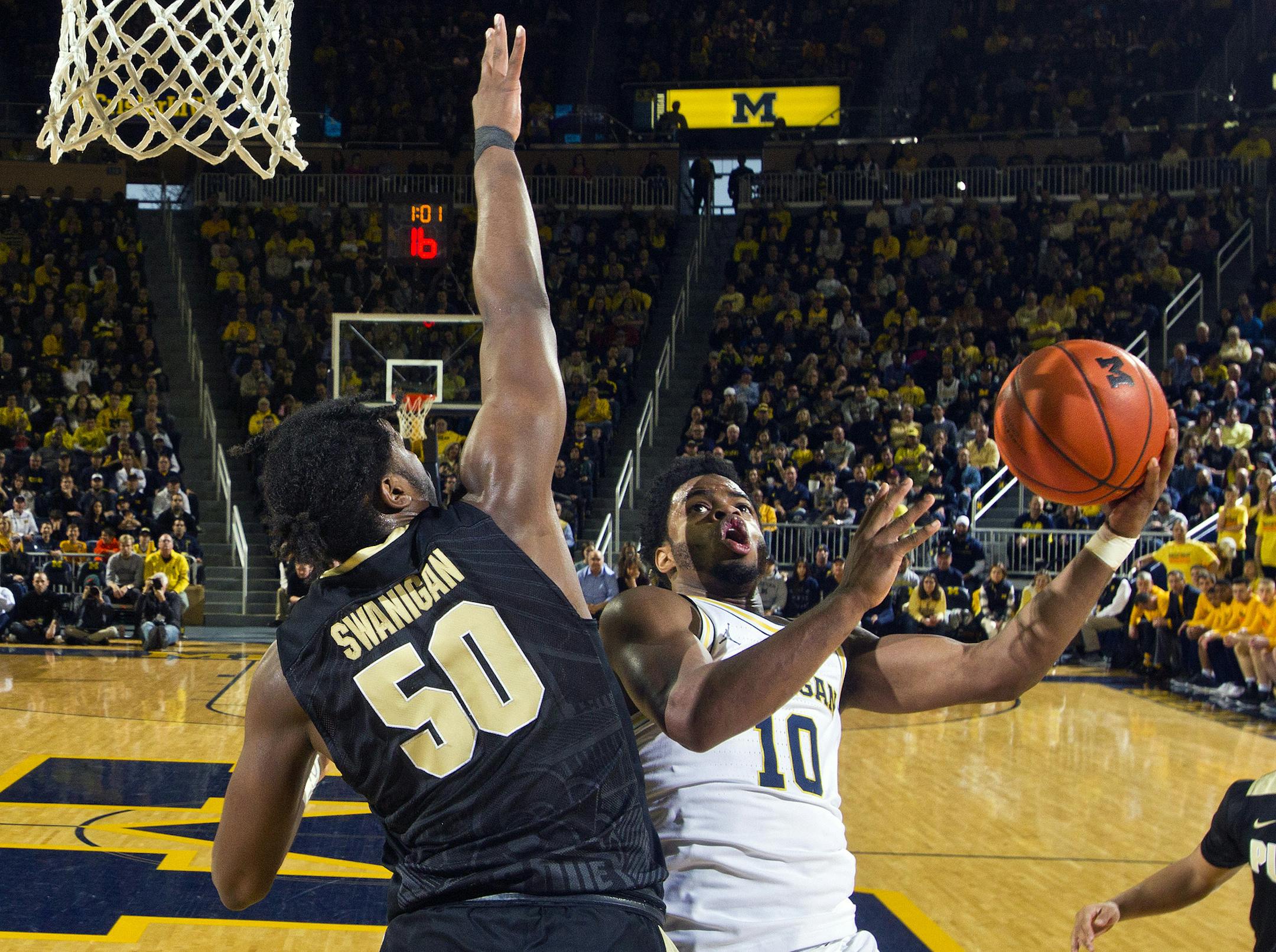 Purdue forward Caleb Swanigan (50) defends against Michigan guard Derrick Walton Jr. (10) under the basket, in the first half of an NCAA college basketball game in Ann Arbor, Mich., Saturday, Feb. 25, 2017. (AP Photo/Tony Ding)