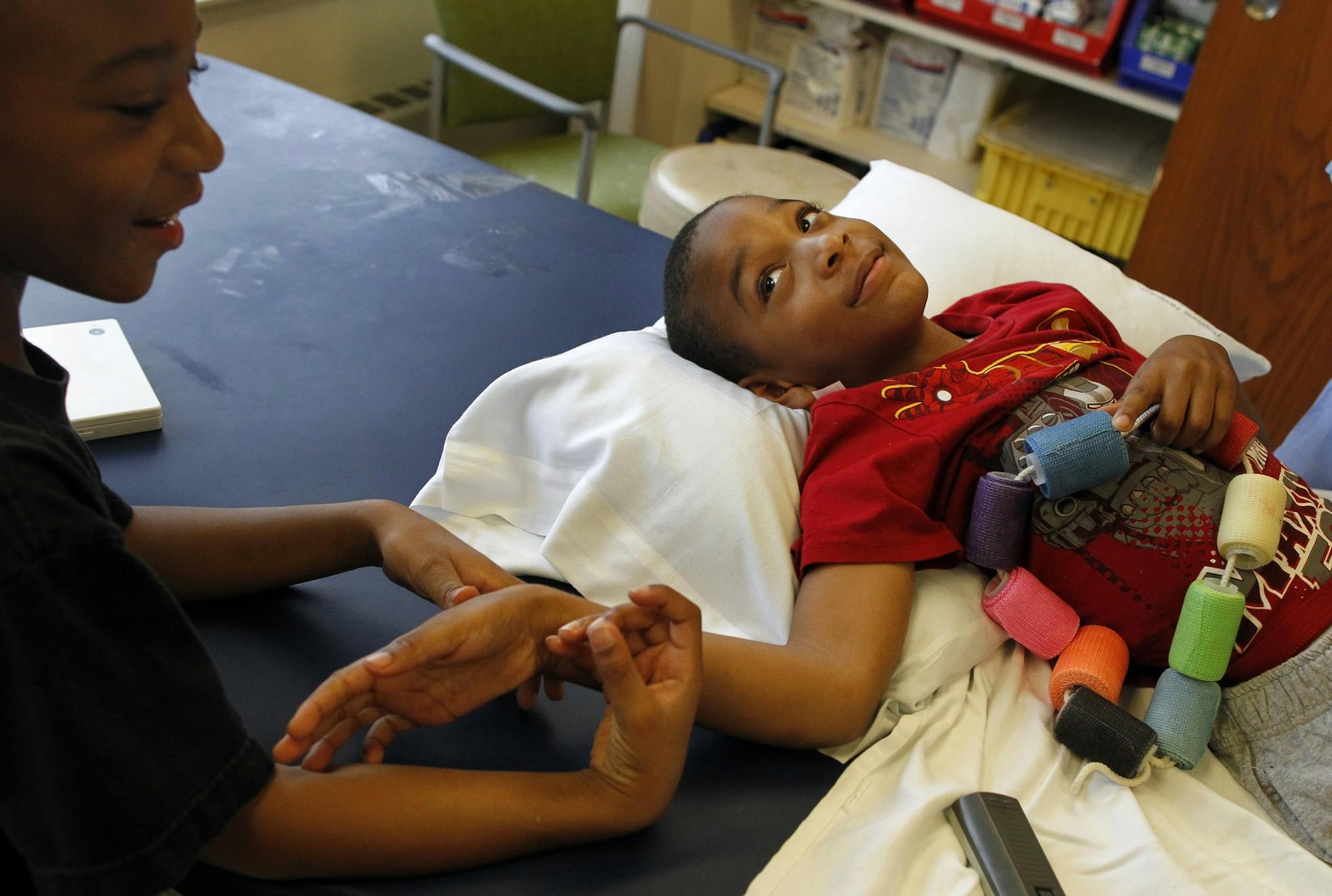 Aaron and Elijah Blasingame, both 7 and identical twins, reached out to each other as Elijah got a new cast made for his legs at Gillette Children's Hospital. The cast is to help Elijah straighten his legs, a complication of cerebral palsy.