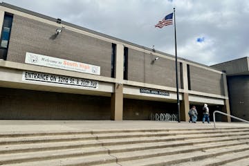 An American flag flies above a brutalist architecture-style building beneath a cloudy sky.