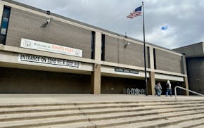 An American flag flies above a brutalist architecture-style building beneath a cloudy sky.