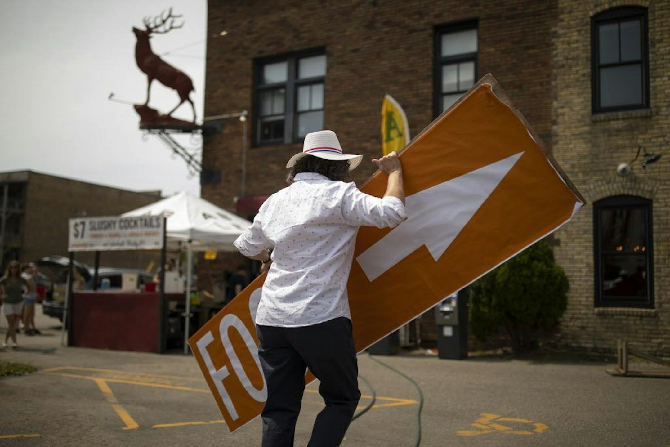 Kim Bartmann carried a sign to be mounted on the side of her restaurant while prepping for Red Stag's 12th annual block party in August.