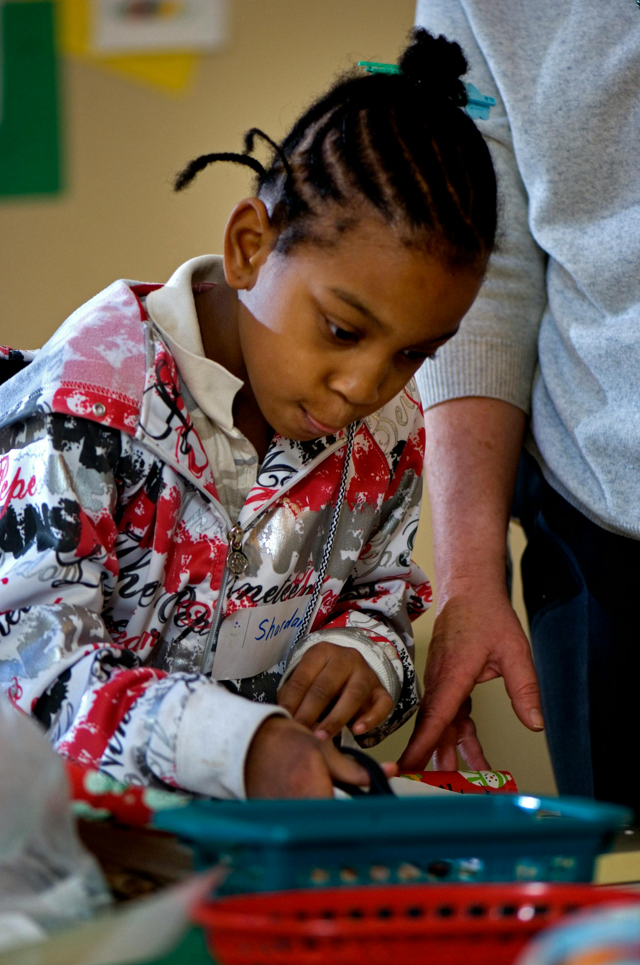 DAVID BREWSTER � dbrewster@startribune.com Wednesday_12/12/07_St.LouisPark Shardai Hall carefully cut off a length of wrapping paper for her present, while General Mills volunteer Elaine Wait held the end of the roll.