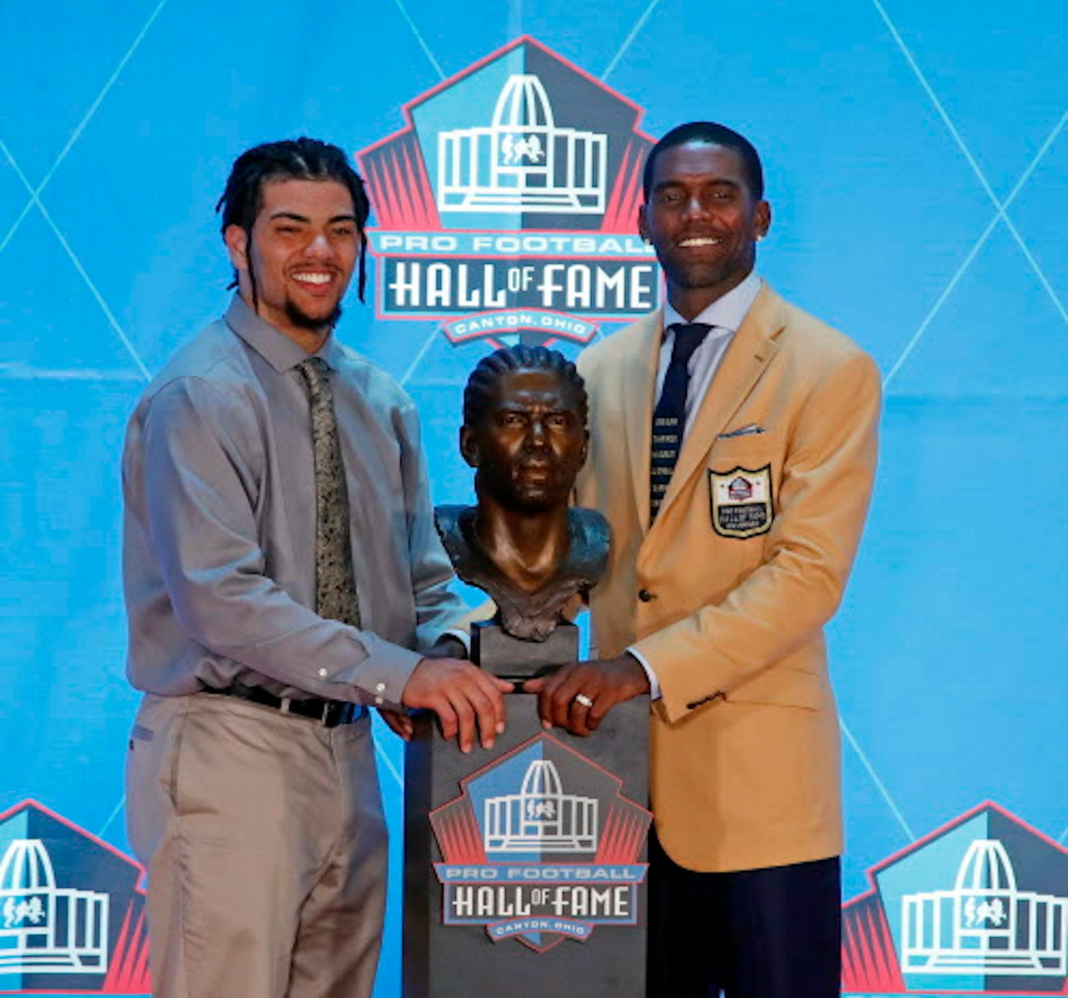 Former NFL player Randy Moss, right, poses with a bust of himself and presenter, son Thaddeus Moss, during an induction ceremony at the Pro Football Hall of Fame, Saturday, Aug. 4, 2018 in Canton, Ohio. (AP Photo/Gene J. Puskar)