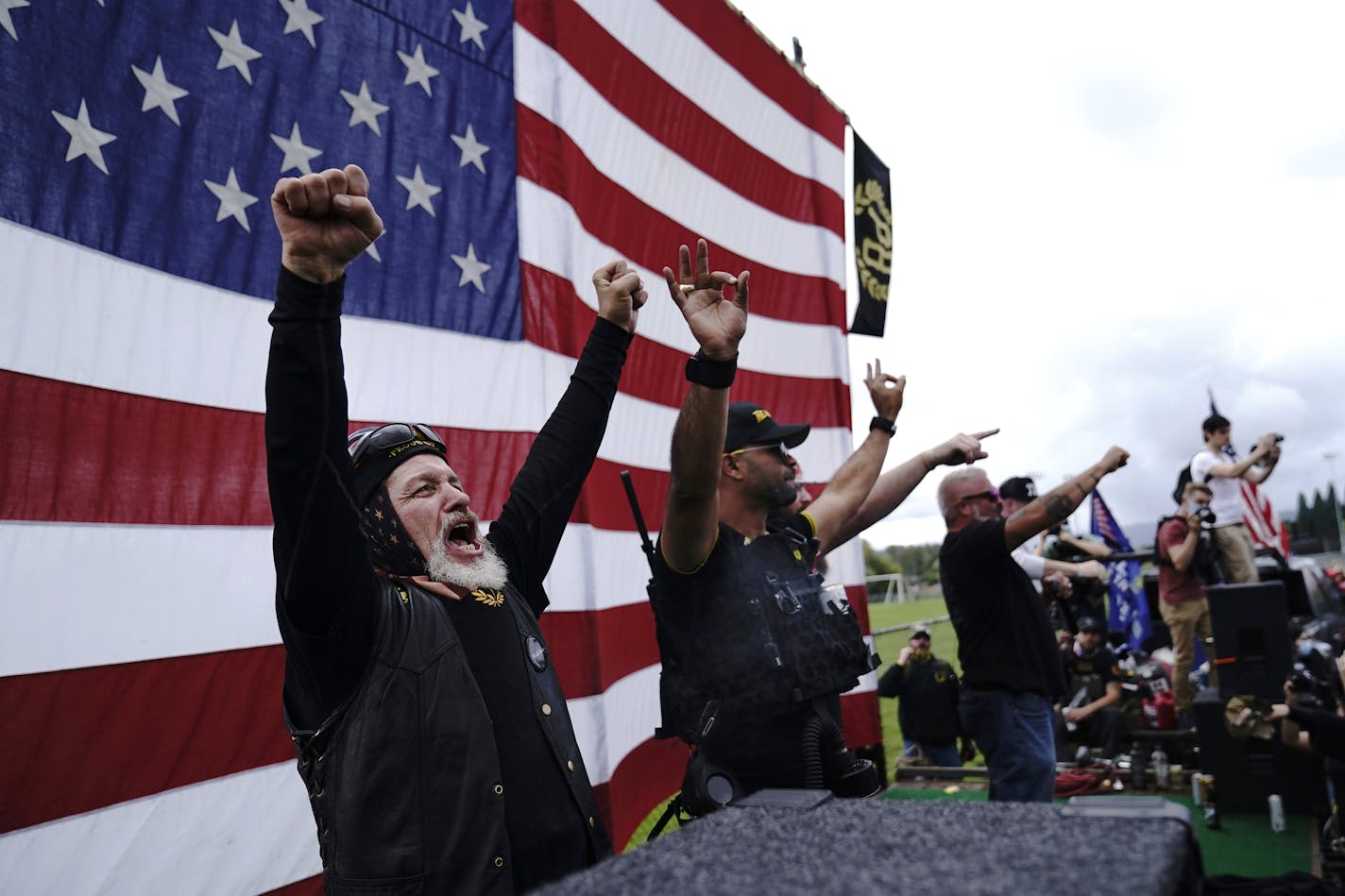 FILE - Members of the Proud Boys cheer on stage as they and other right-wing demonstrators rally, Saturday, Sept. 26, 2020, in Portland, Ore. President Donald Trump didn't condemn white supremacist groups and their role in violence in some American cities this summer. Instead, he said the violence is a "left-wing" problem and he told one far-right extremist group to "stand back and stand by." His comments Tuesday night were in response to debate moderator Chris Wallace asking if he would condemn