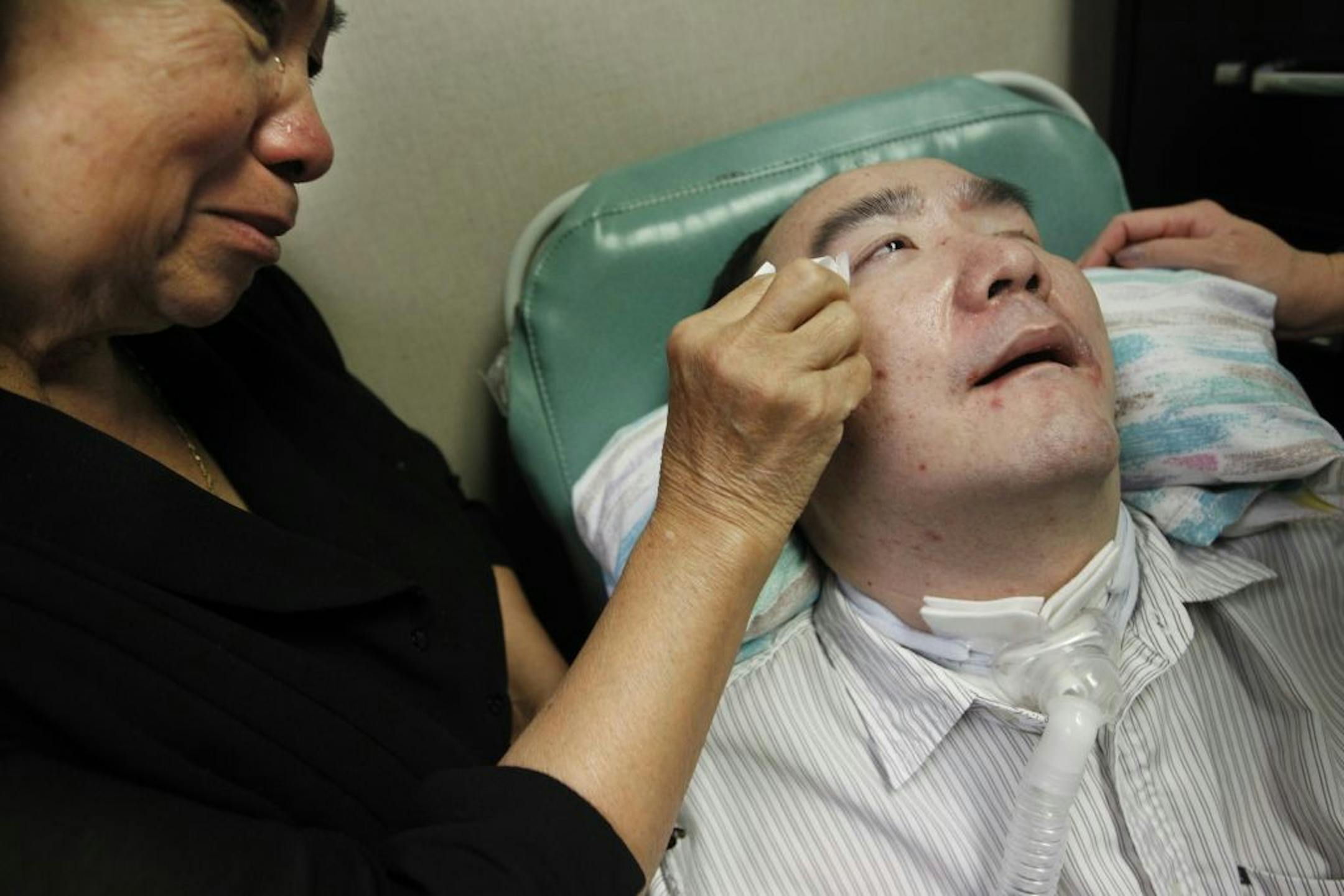 Ying Xiong worried how an impending cut in state will affect the care of her son Kee Vang, who has been in a coma after a heart attack several years ago.