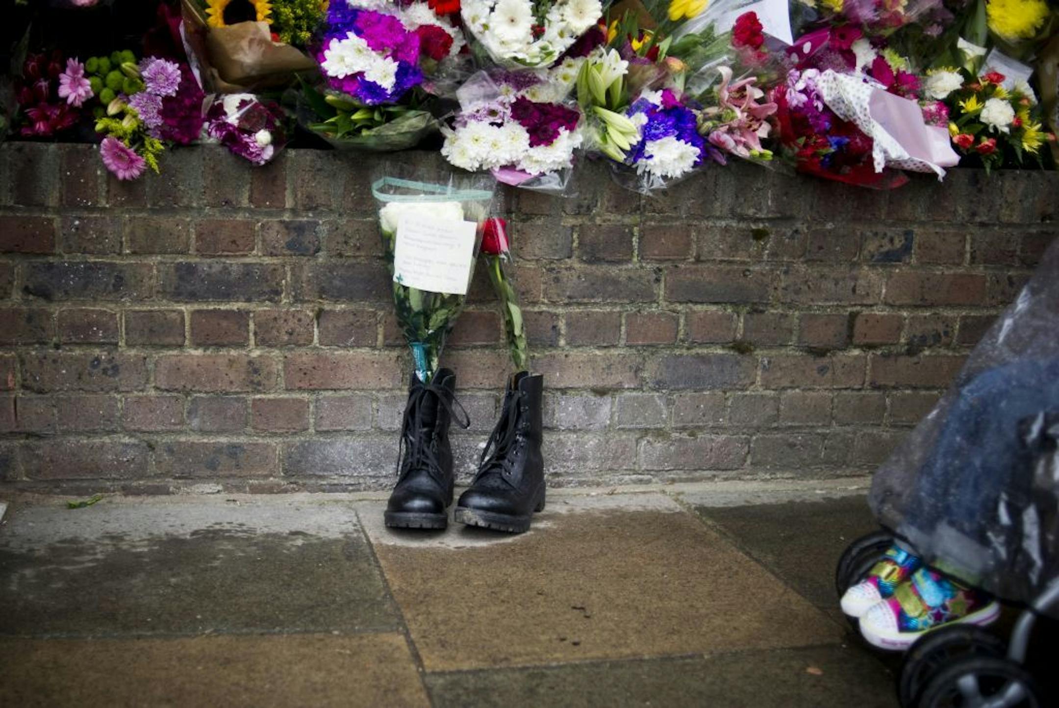 FILE - In this Friday, May 24, 2013 file photo, military boots are laid in tribute outside the Woolwich Barracks, in London, in response to the bloody attack on Wednesday when a British soldier was killed in the nearby street. Counterterrorism police on Saturday were questioning a friend of Michael Adebolajo, one of two suspects in the savage killing of British soldier Lee Rigby. The friend, Abu Nusaybah, was arrested immediately after he gave a television interview telling his story about how A