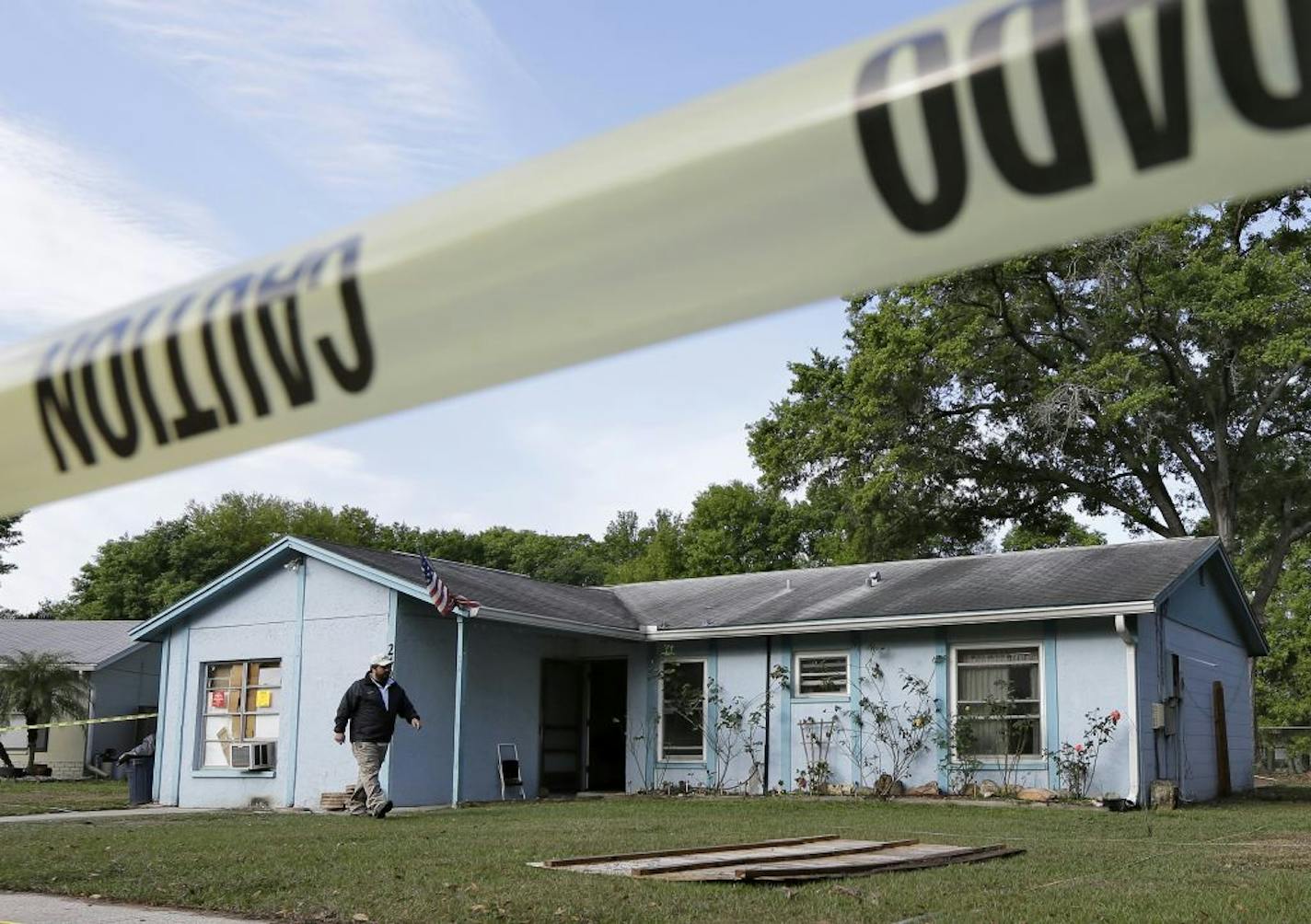 An engineer surveys in front of a home where sinkhole opened up on Friday, March 1, 2013, in Seffner, Fla. A man screamed for help and disappeared as a large sinkhole opened under the bedroom of the house, his brother said Friday.