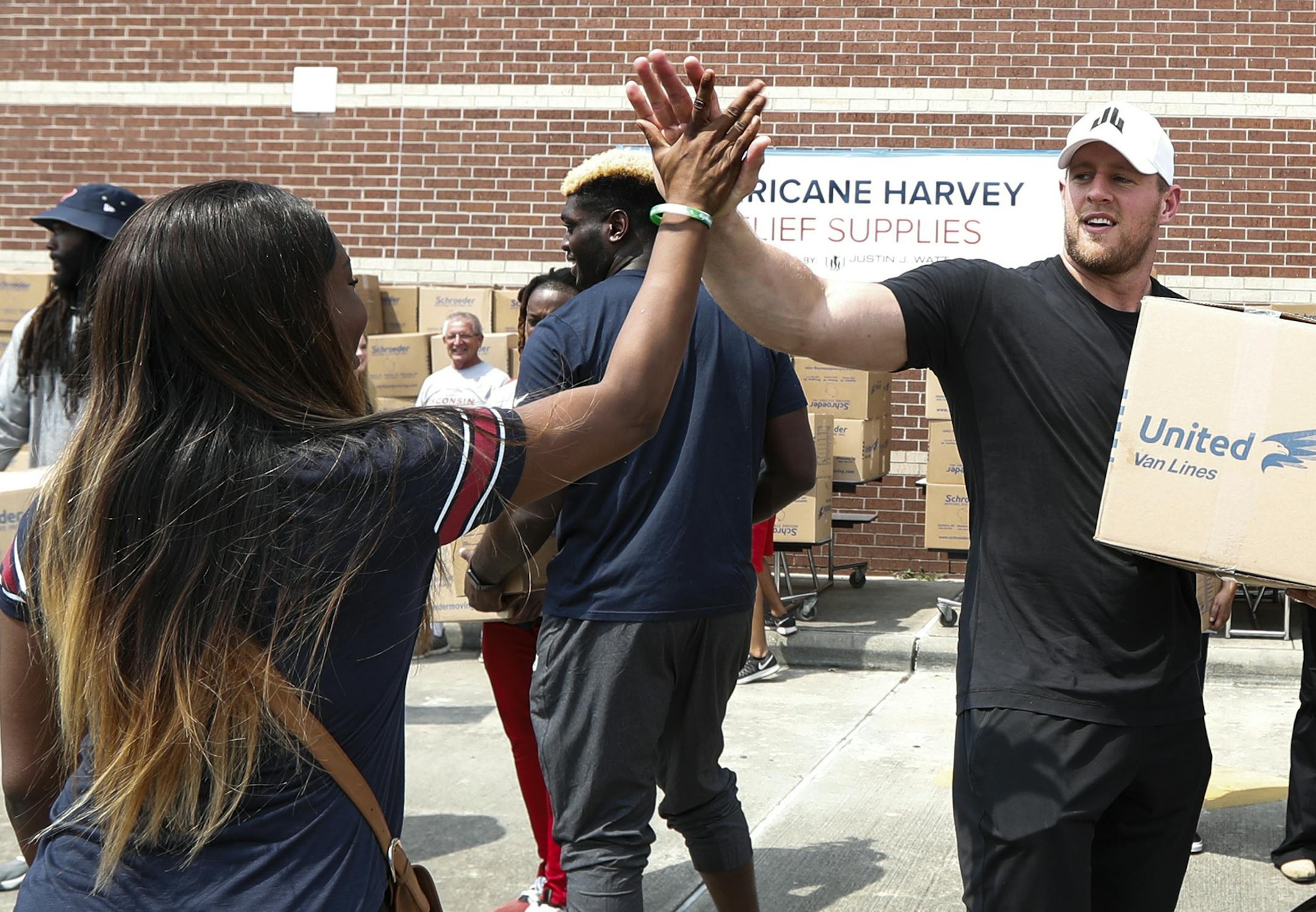 Anna Ucheomumu, left, high fives Houston Texans defensive end J.J. Watt after loading a car with relief supplies to people impacted by Hurricane Harvey on Sunday, Sept. 3, 2017, in Houston. Watt's Hurricane Harvey Relief Fund has raised millions of dollars to help those affected by the storm. (Brett Coomer/Houston Chronicle via AP, Pool)