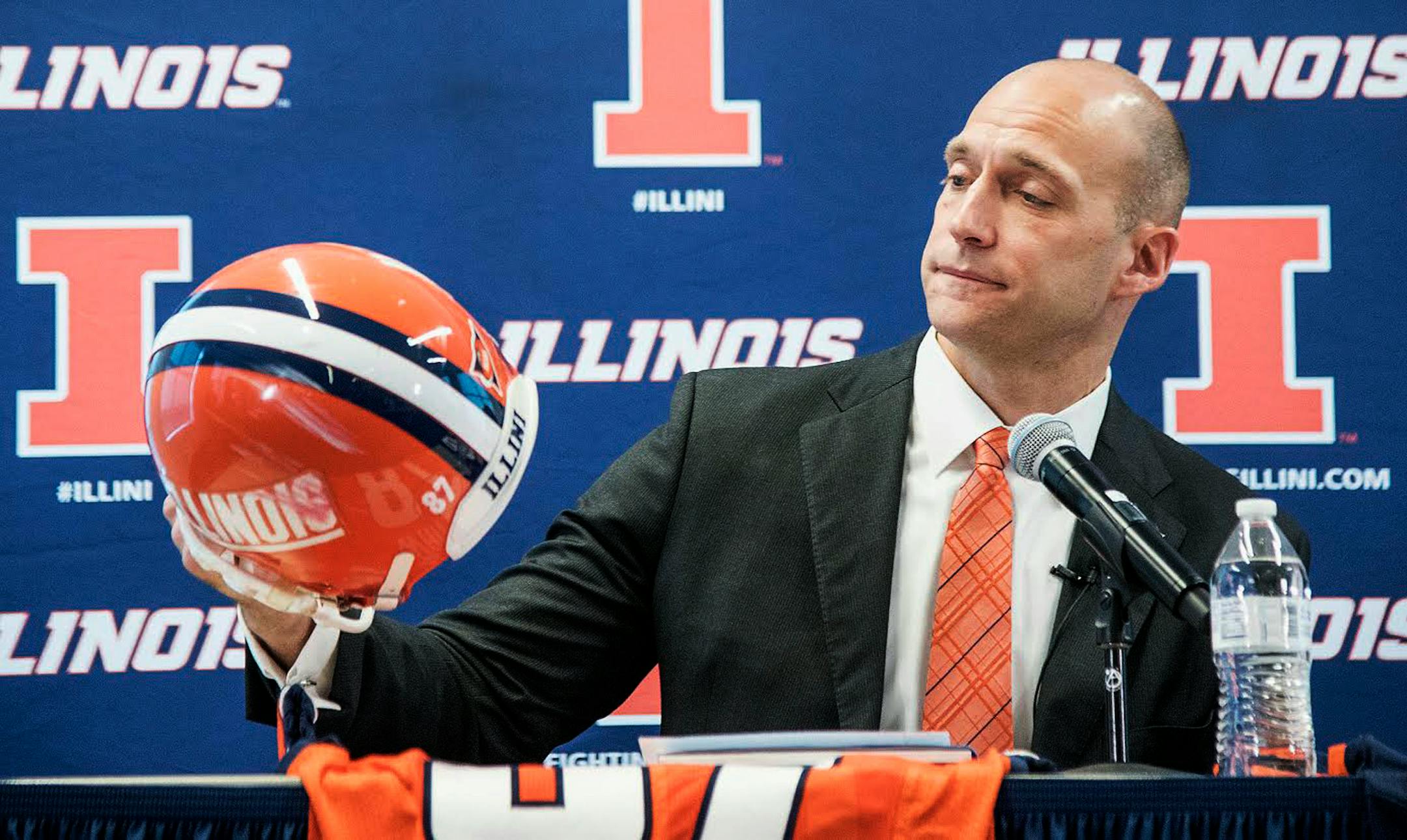 Josh Whitman, holds up his old football helmet as he is announced as the new the new Illinois athletic director during a news conference at Bielfeldt Athletic Administration Building in Champaign, Ill., Thursday, Feb. 18, 2016. The 37-year-old former Illinois and NFL player was most recently the athletic director at Washington University in St. Louis. (Heather Coit/The News-Gazette via AP) MANDATORY CREDIT