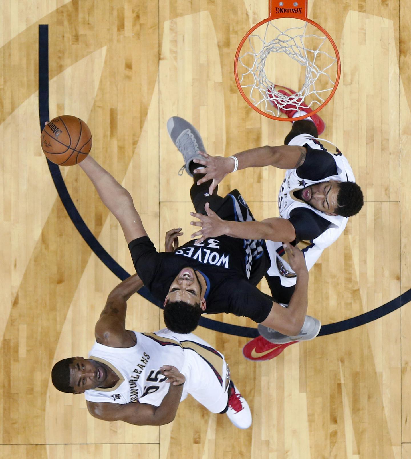 Minnesota Timberwolves center Karl-Anthony Towns (32) goes to the basket between =New Orleans Pelicans guard E'Twaun Moore (55) and forward Anthony Davis in the second half of an NBA basketball game in New Orleans, Sunday, March 19, 2017. The Pelicans won 123-109. (AP Photo/Gerald Herbert)