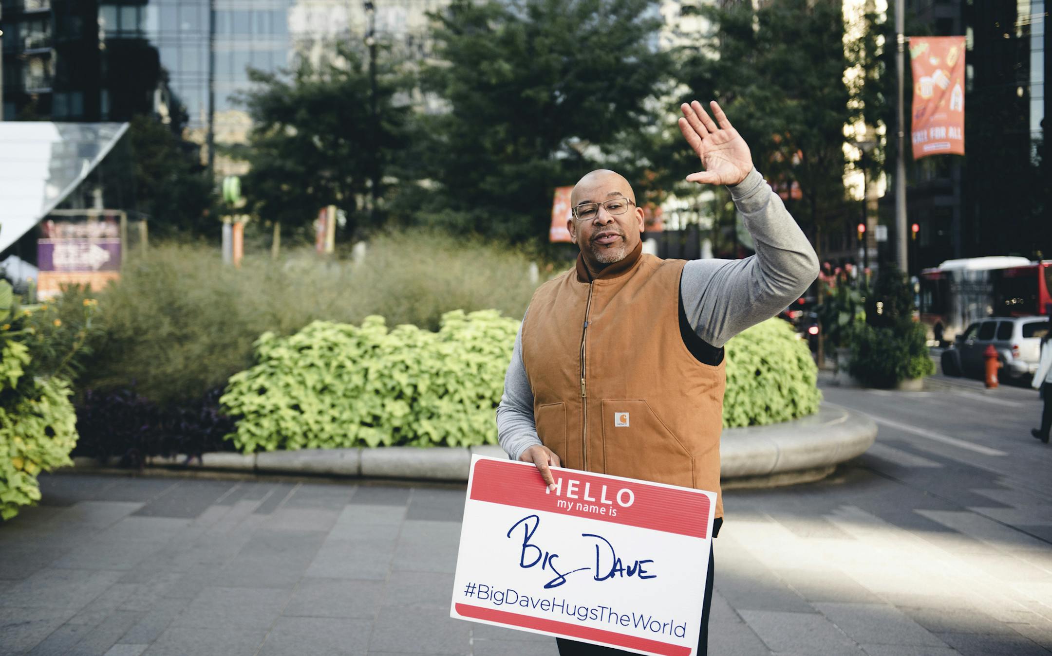 In this Oct. 19, 2018, photo, David "Big Dave" Sylvester hold a sign that reads, "Hello, my name is Big Dave," in Philadelphia. #BigDaveHugsTheWorld," he believes its his smile that serves as the most powerful tool in getting people to let down their guard.