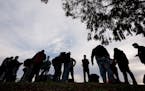 Migrants stood in groups as they arrived at a bus stop after leaving a processing facility, Friday, Feb. 23, 2024, in San Diego. Hundreds of migrants 